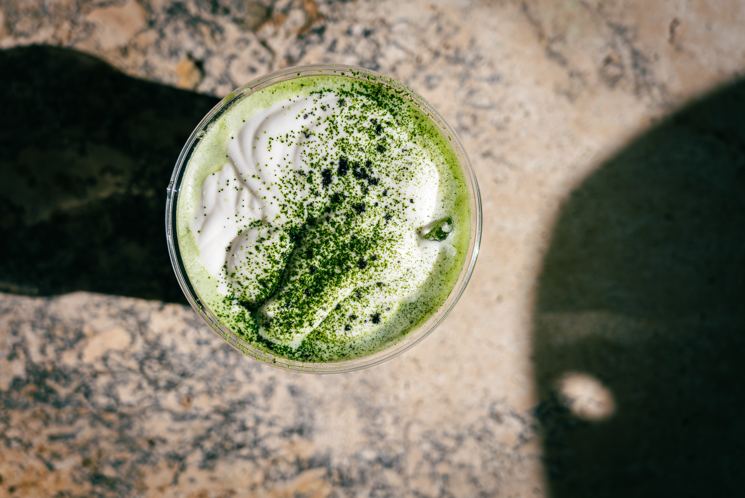 Top-down view of an iced matcha with cream top and matcha powder dusting
