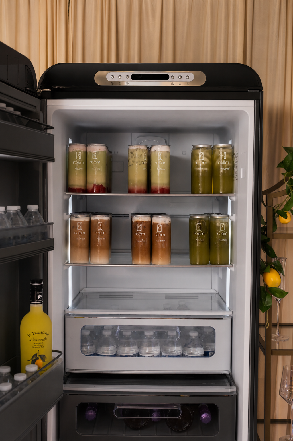 Open refrigerator with various bottled beverages inside, including green, brown, and red layered drinks on shelves and bottled water at the bottom.