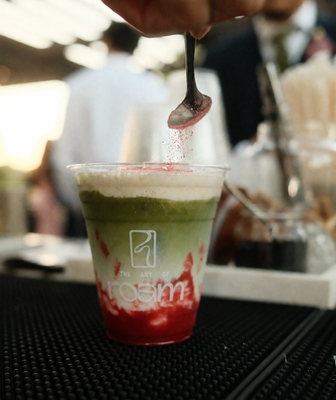 Strawberry matcha latte with house-made fruit purée being finished at a private catering event.