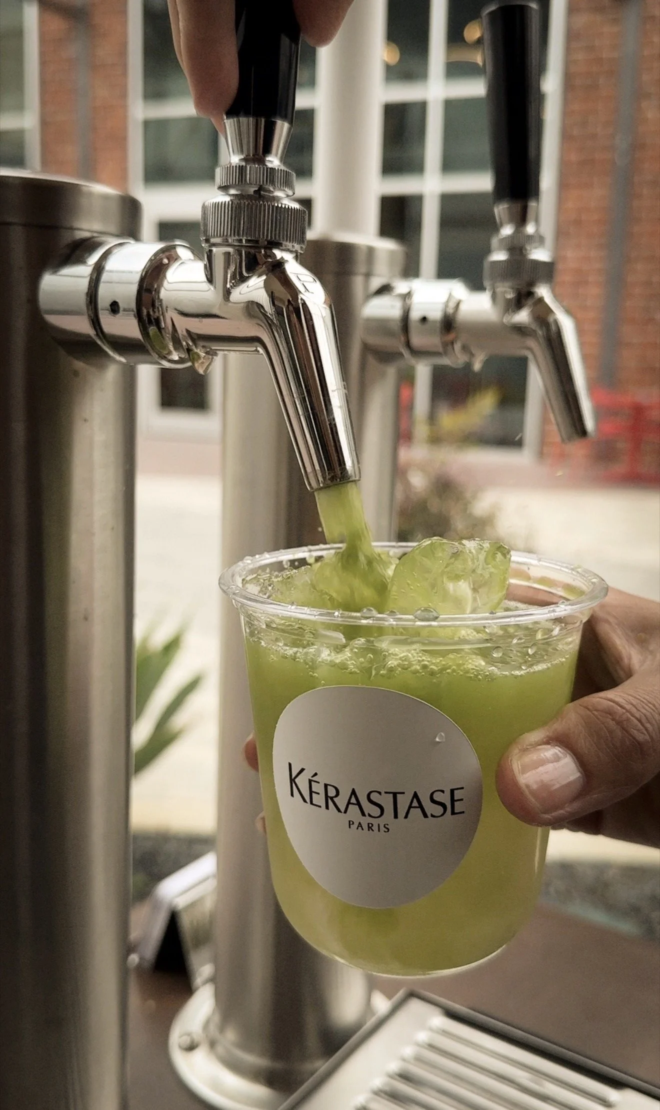 Fresh matcha being poured from a draft tap into a custom-branded Kérastase cup at a corporate event.