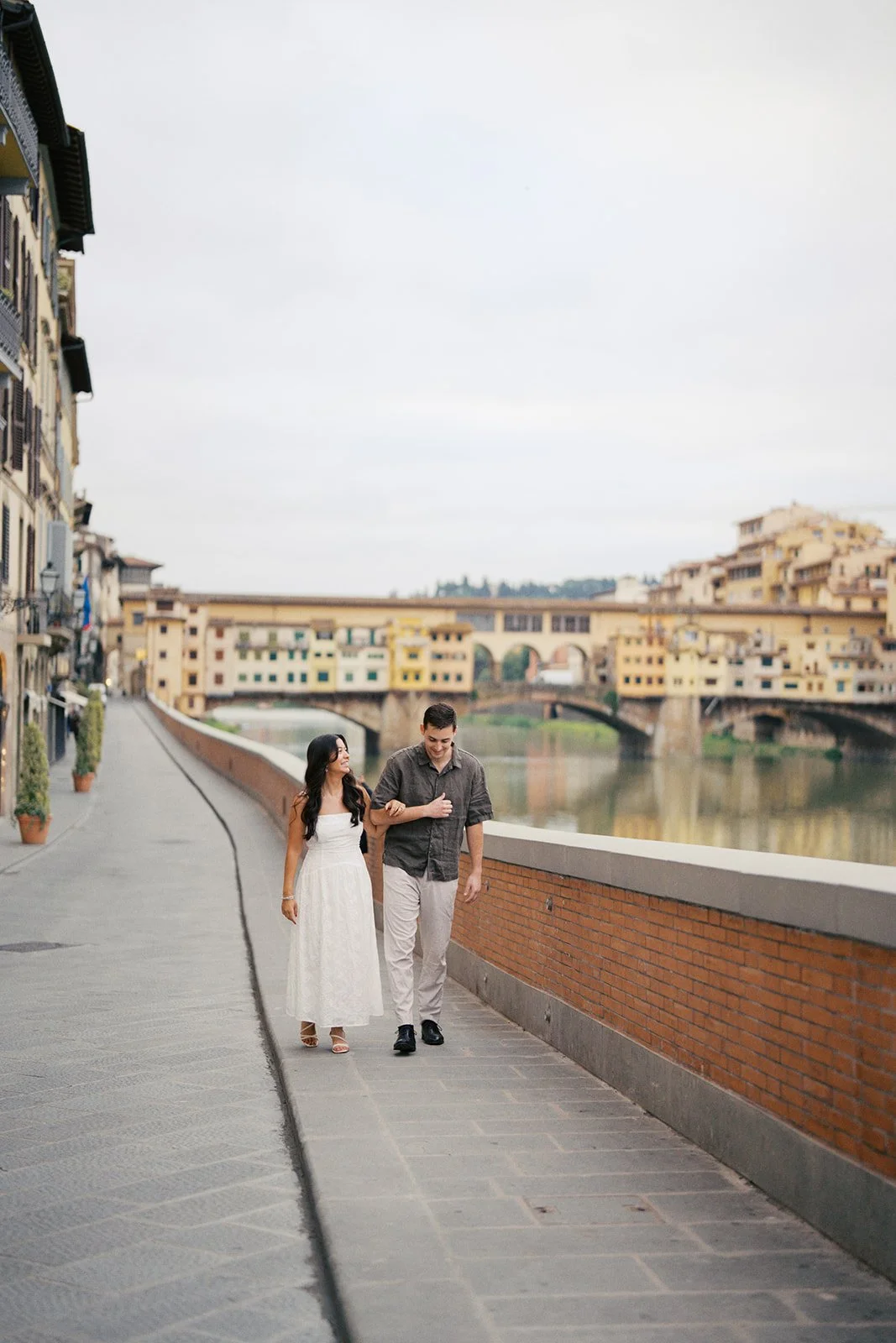couple hand-in-hand by arno river in florence, italy