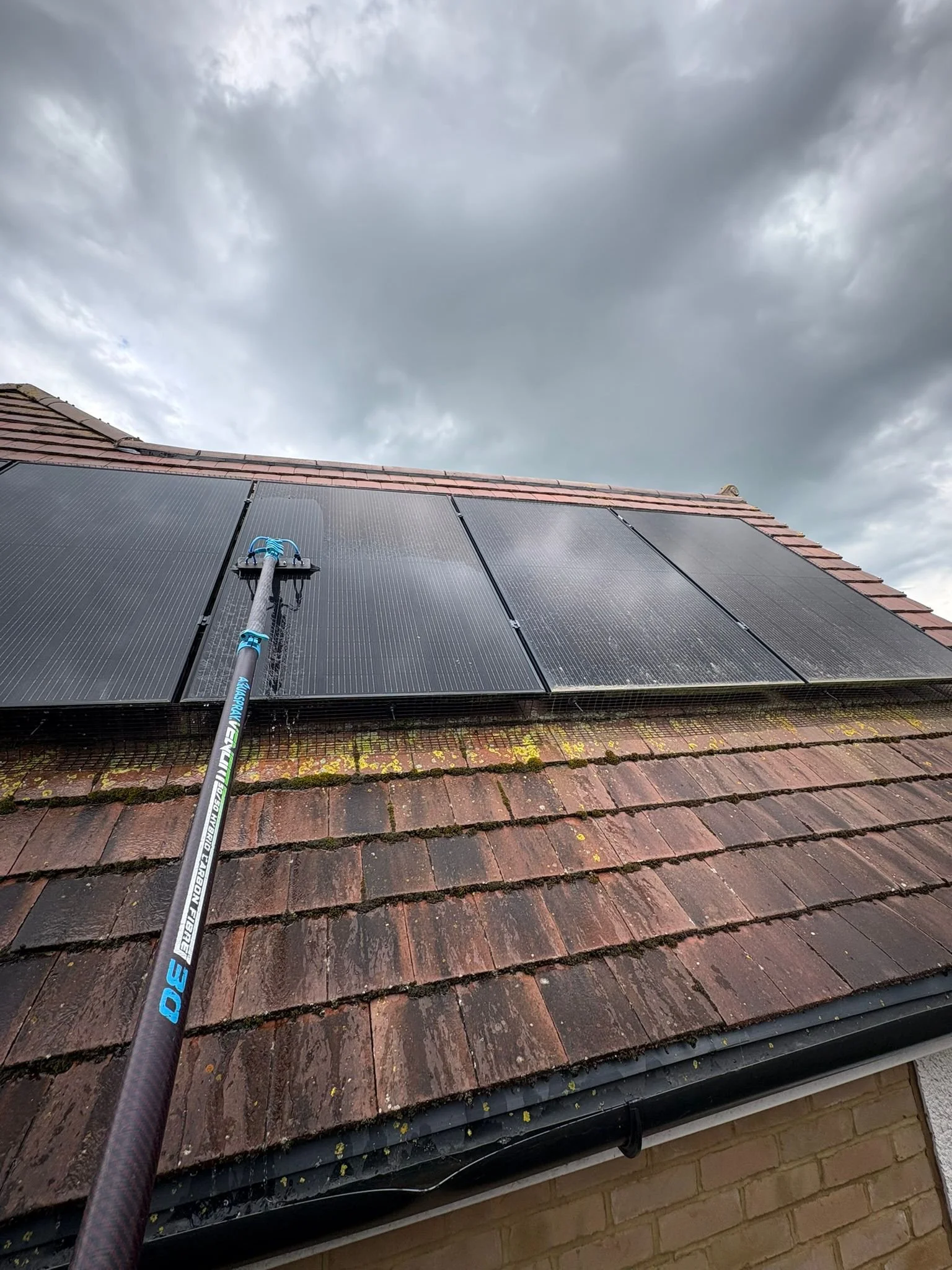 Close-up view of solar panels installed on a rooftop with dark cloudy sky in the background.