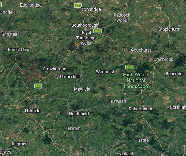 Satellite map of a rural area in England showing towns, villages, roads, and the High Weald National Landscape.