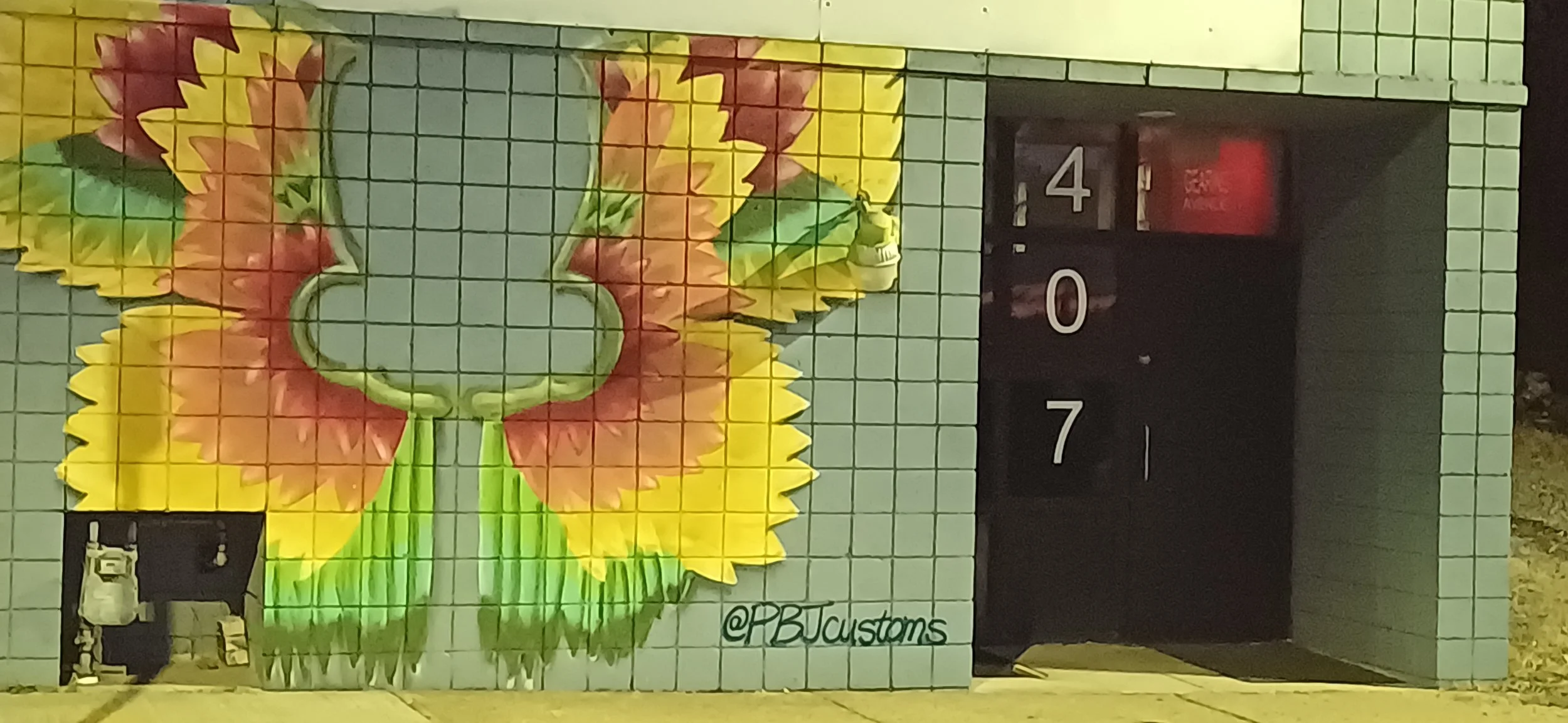 Community meetings where Colorful mural of a butterfly painted on a light blue tiled wall with a door and the artist's signature '@PBCustoms' in the bottom right corner.