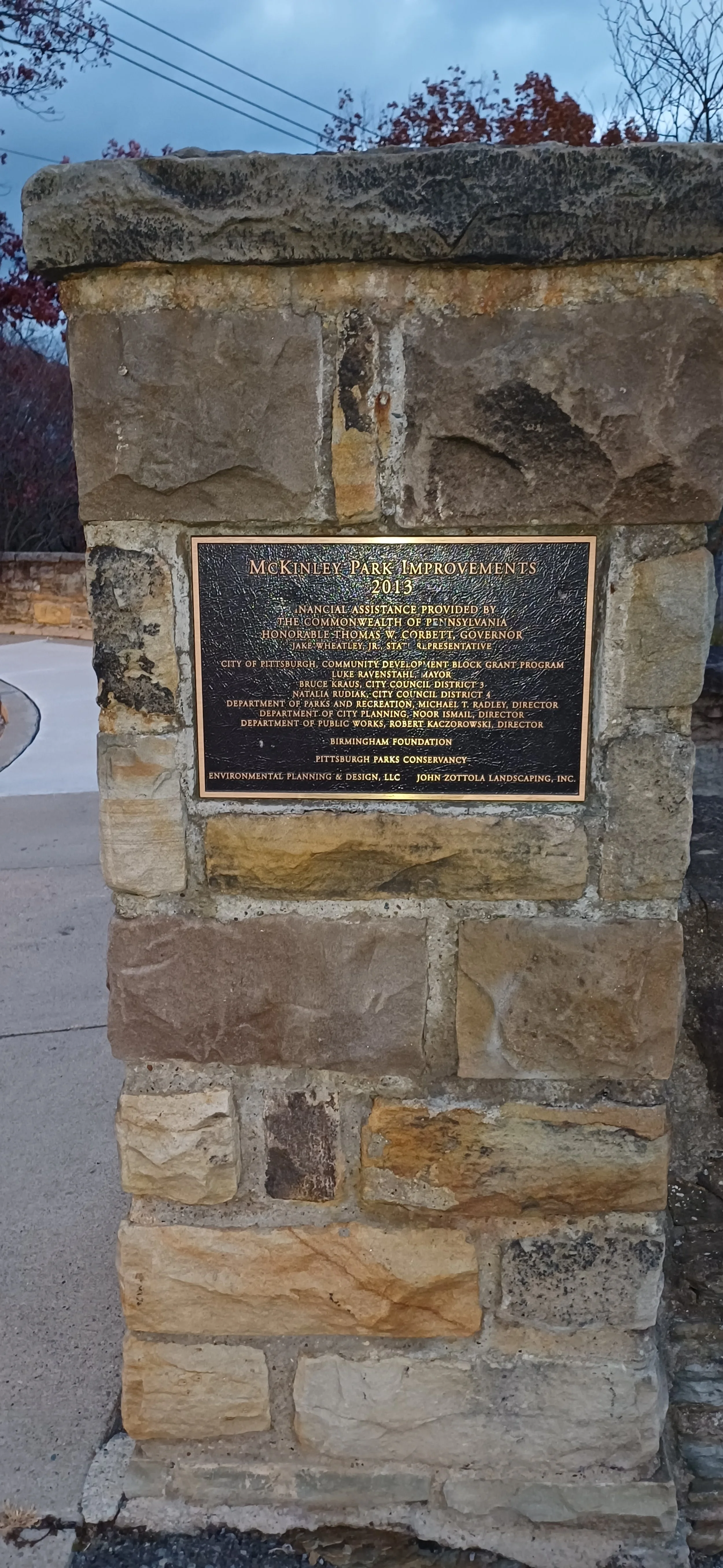 Stone pillar with a black and gold plaque commemorating McKinley Park improvements in 2013, funded by various city and state agencies, and designed by Environmental Planning & Design, LLC and John Zottola Landscaping, Inc.