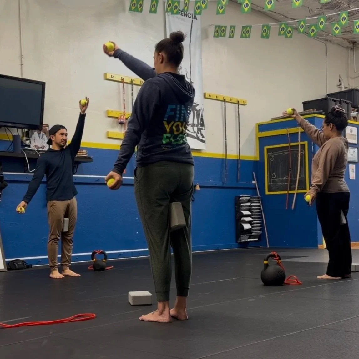 Three people practicing shoulder mobility exercise in a gym