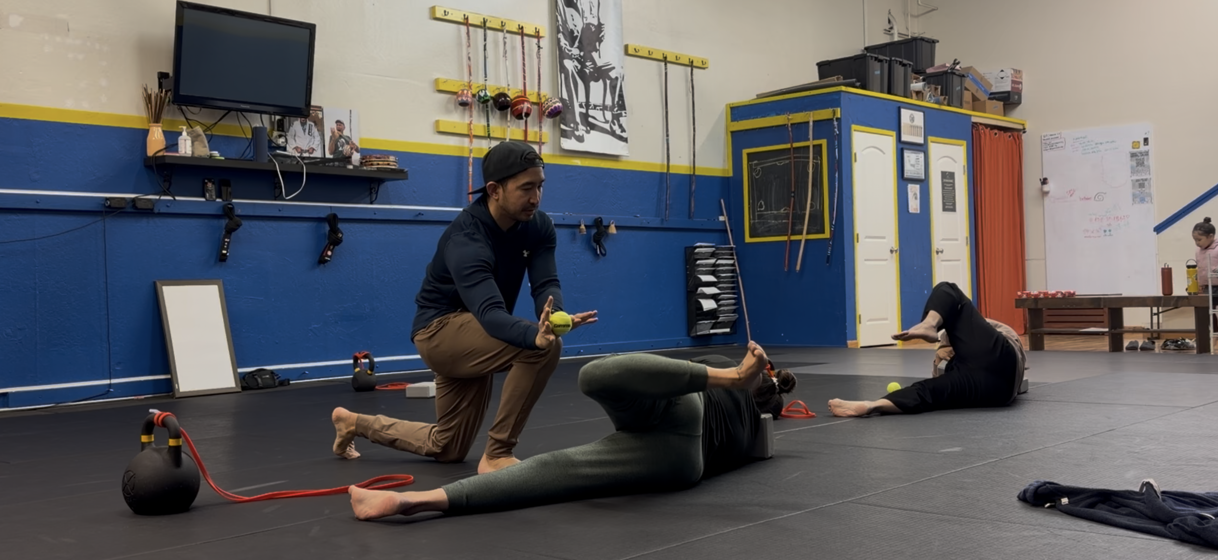 Coach Alfred guiding two people through exercises in a gym