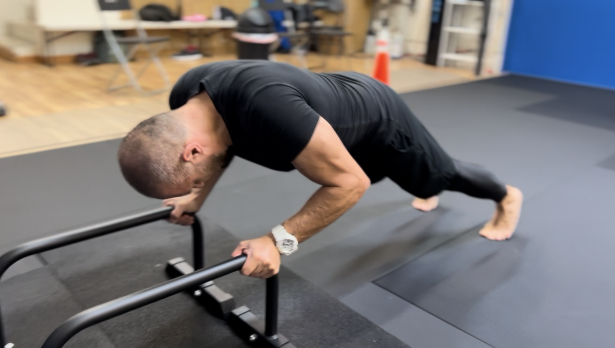 Man performing push-up exercise on a push-up bar in a gym.