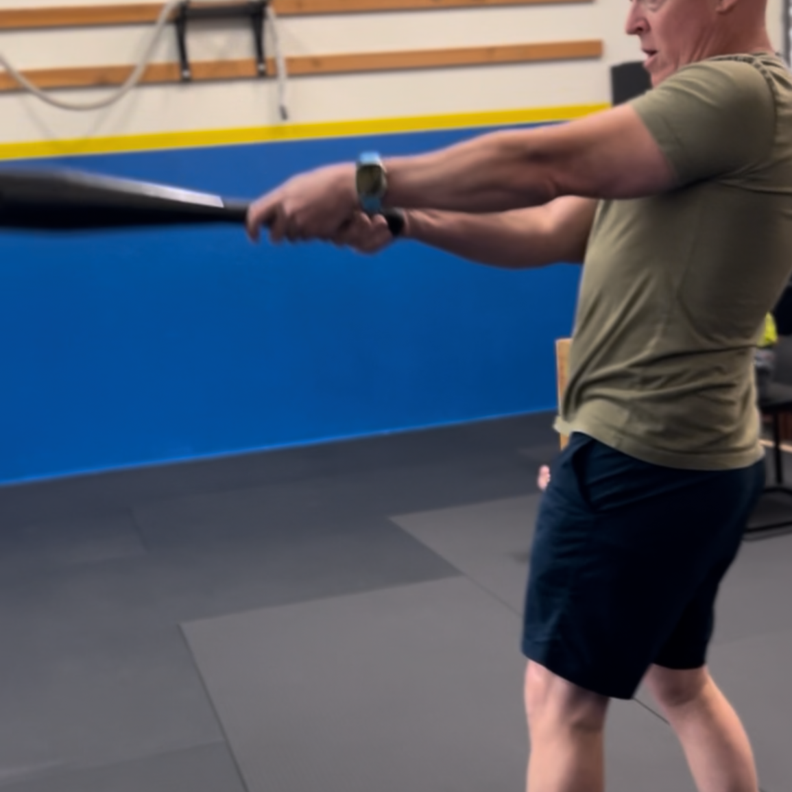 Man in a gym swinging a clubbell during exercise.