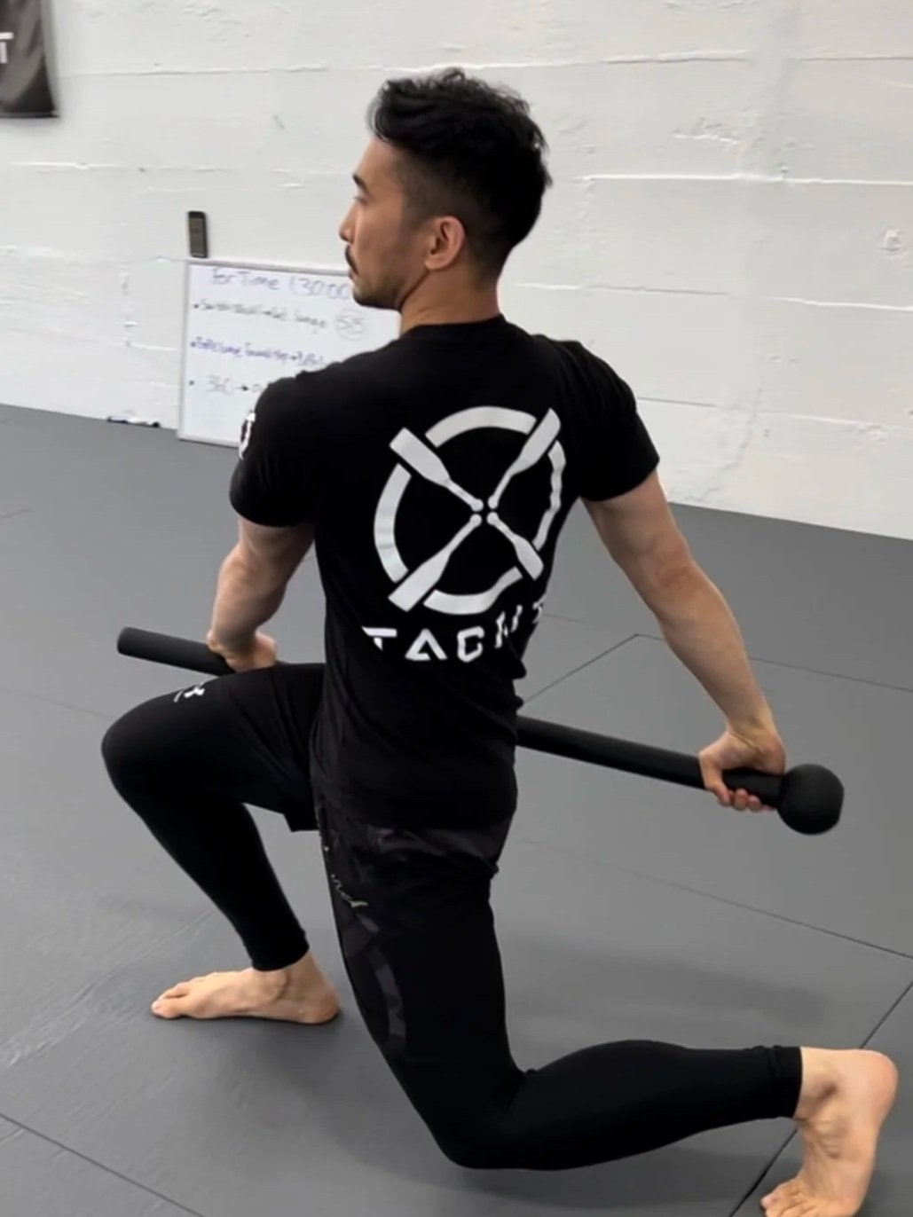 A man performing steel mace lunge exercise