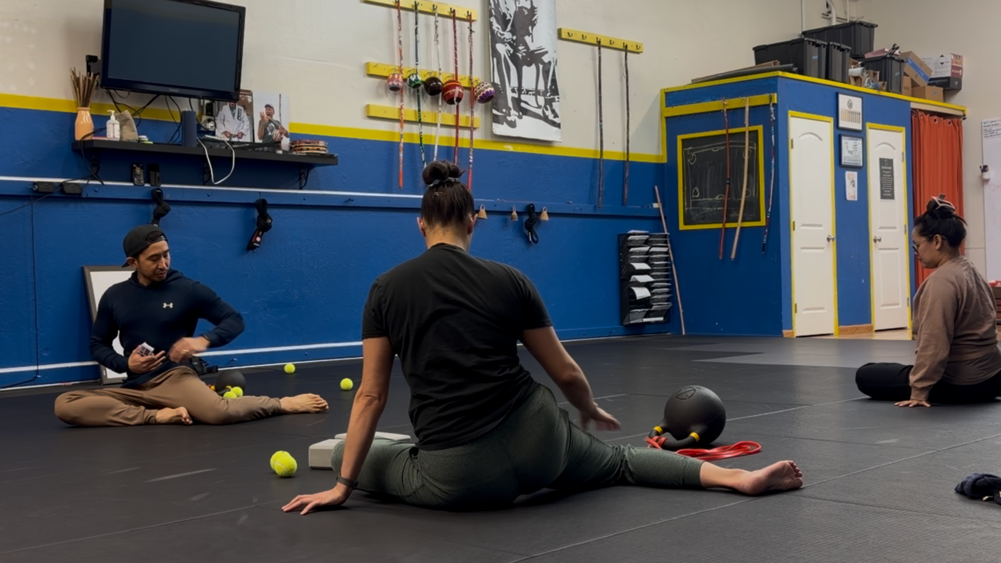 People sitting on the floor inside a fitness studio, participating in a Kinstretch class