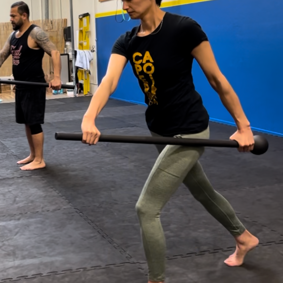 A woman and a man practicing fitness exercises with steel mace in a gym.