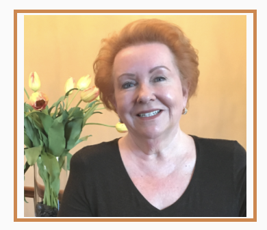 Judy Goodman sitting in front of a vase of yellow and white tulips.