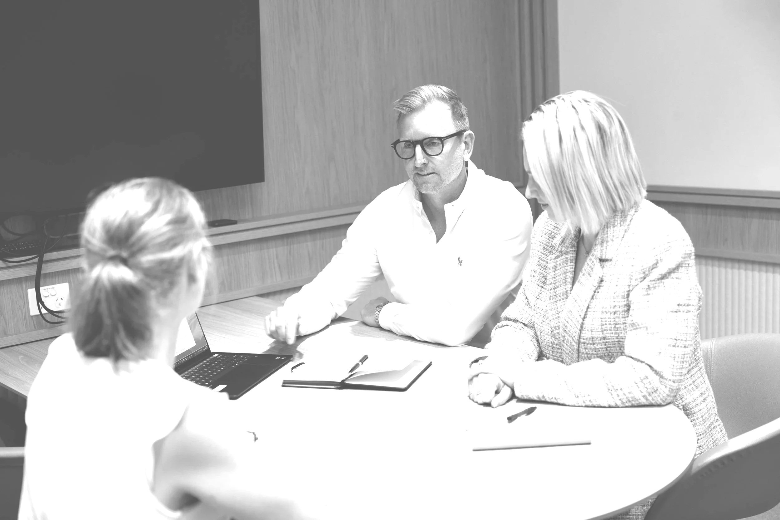 Three people sitting at a table having a discussion in a conference room.