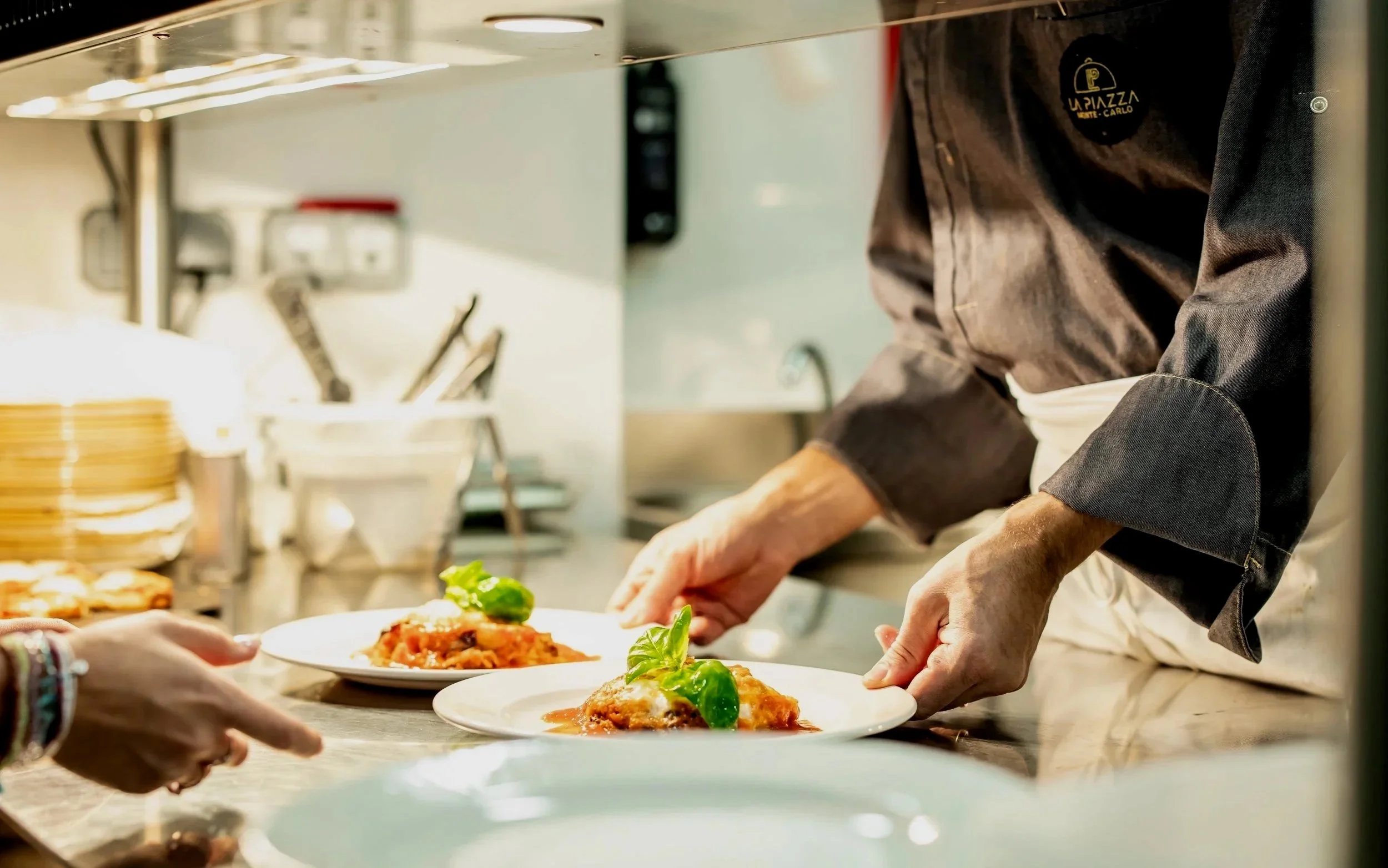 Chef plating dishes in a restaurant kitchen.