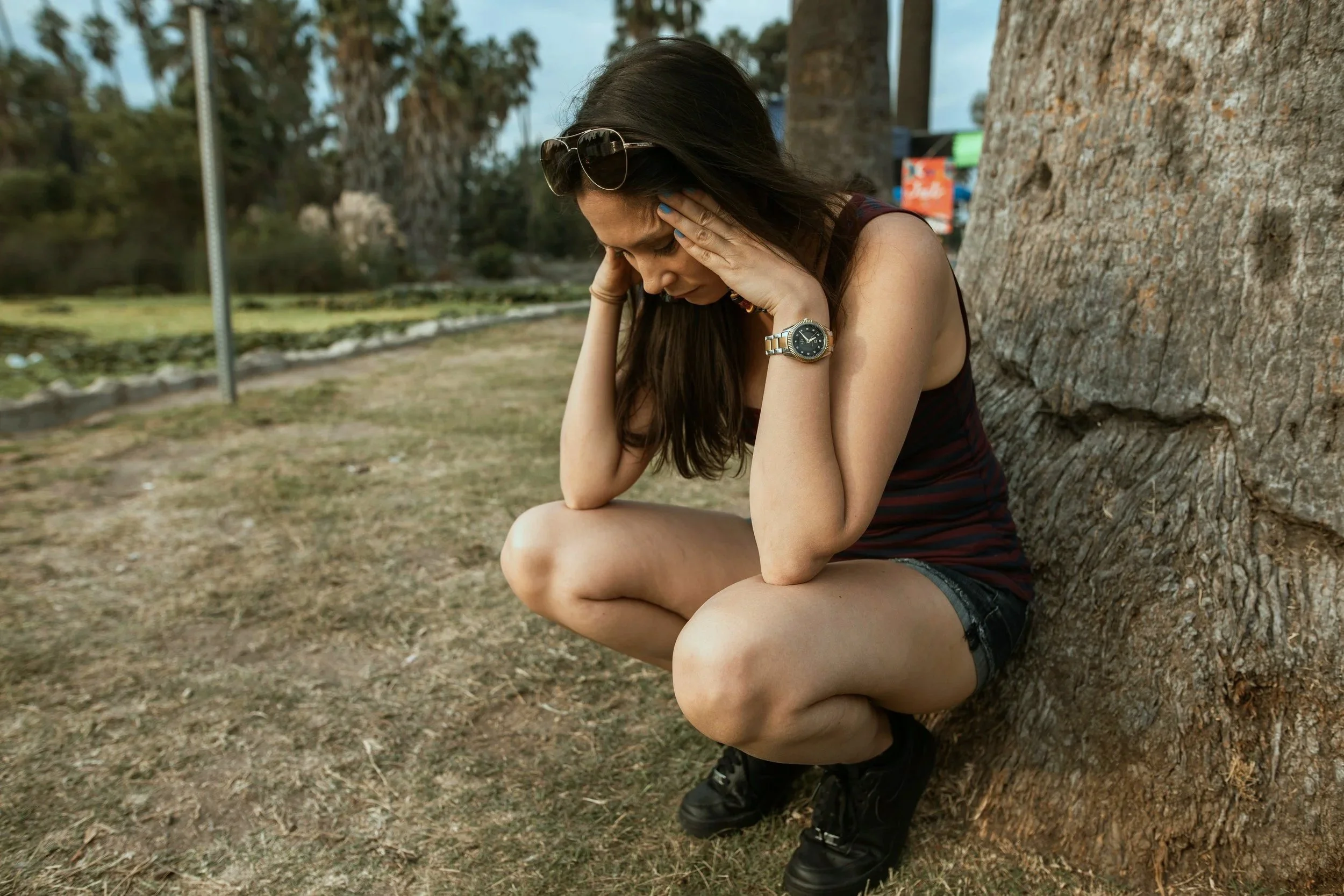 Stressed woman pauses by a tree