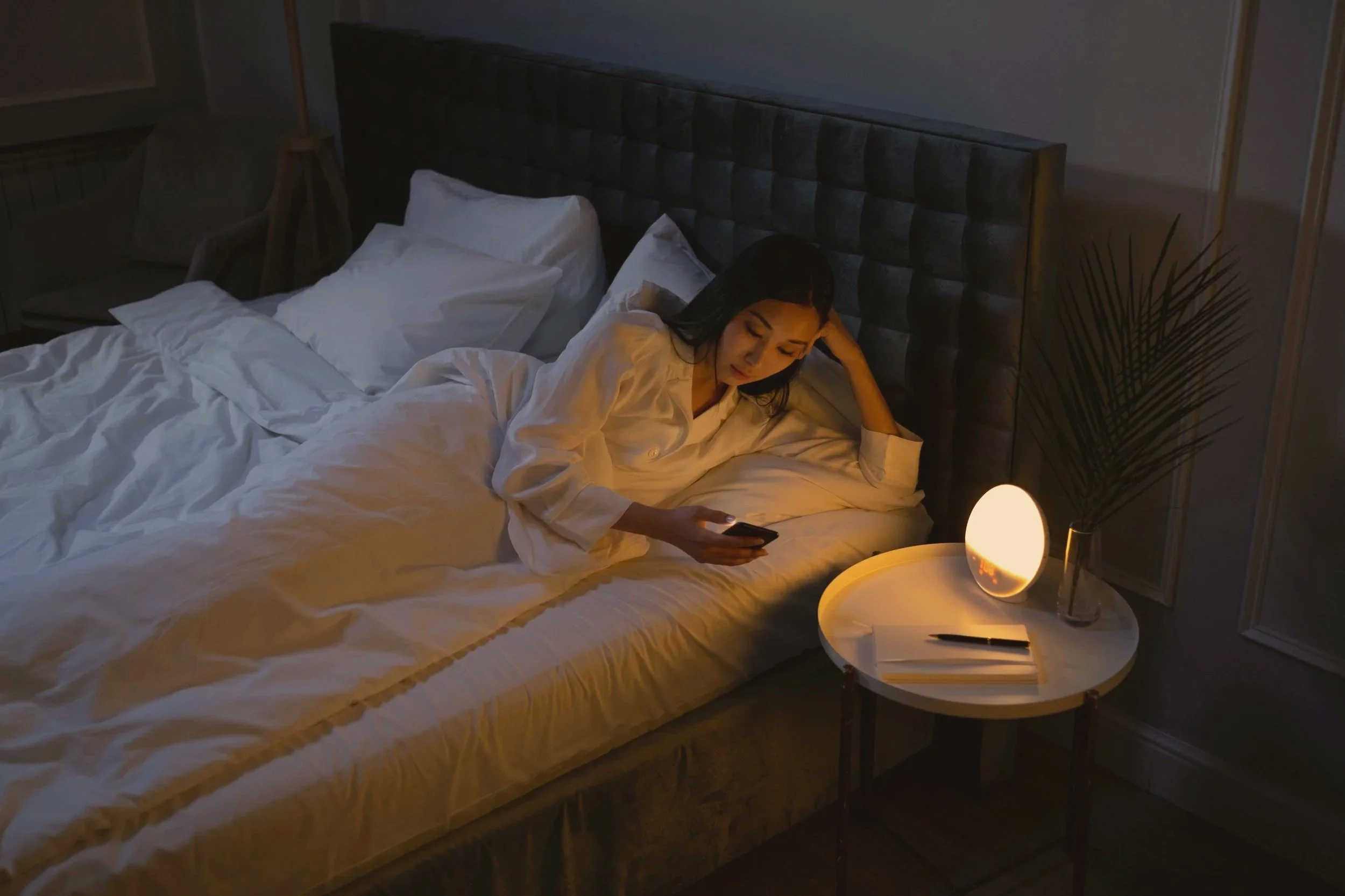 Woman lying in bed looking at her phone