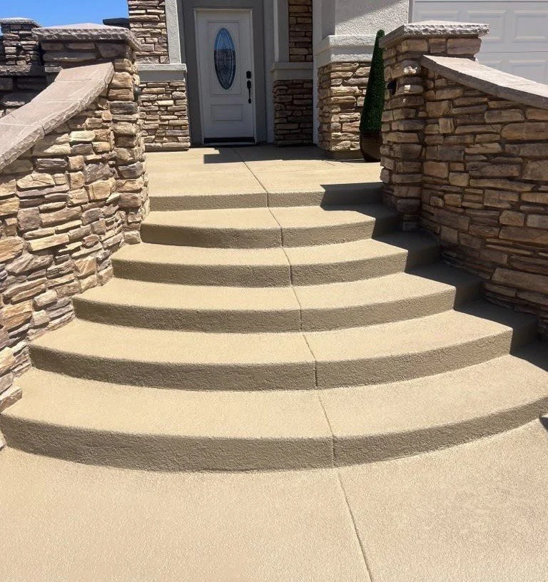 Concrete stairs leading up to a front door with stone brick walls on both sides.