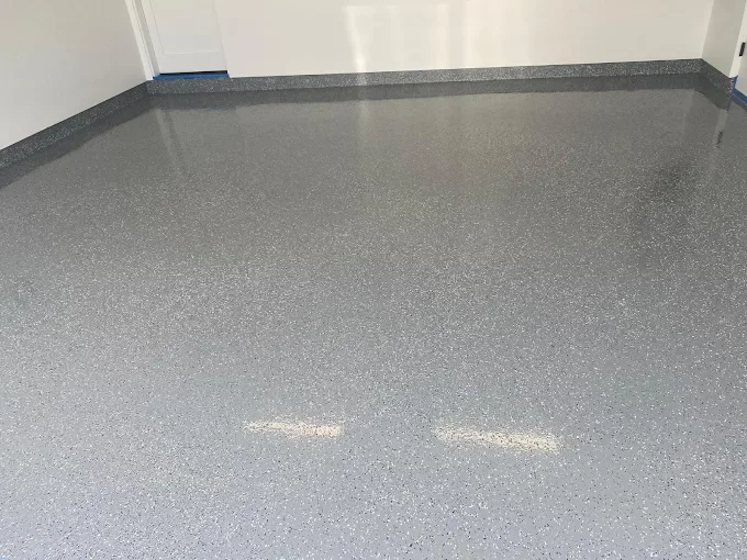 Empty room with gray speckled epoxy flooring and white walls.