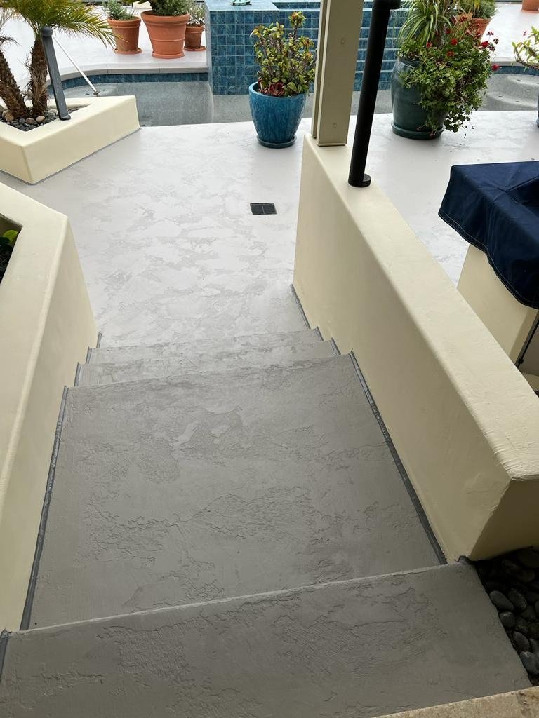 Concrete stairs leading to an outdoor patio with potted plants and a blue tile water feature.