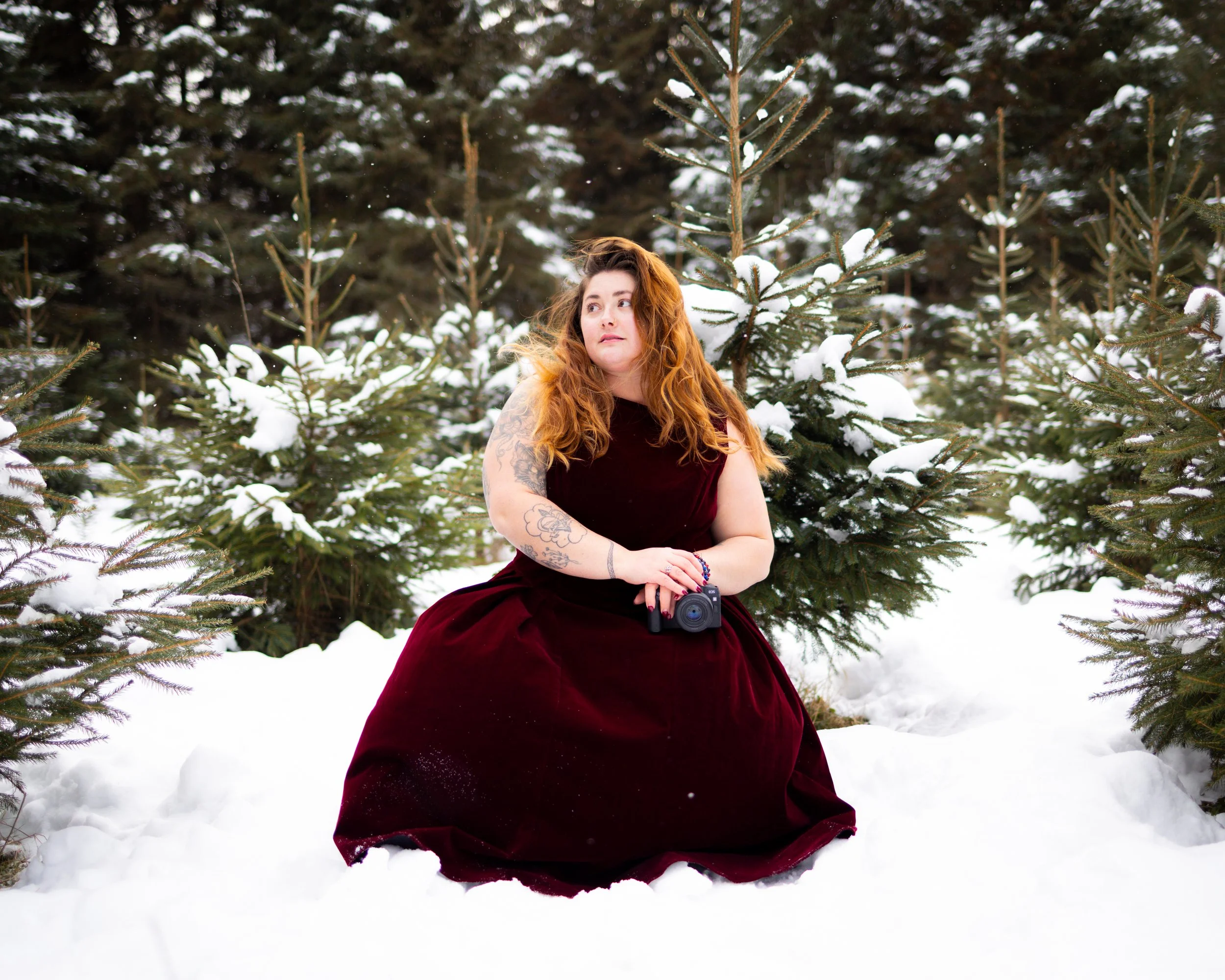 Red hair girl in a red dress holding a camera