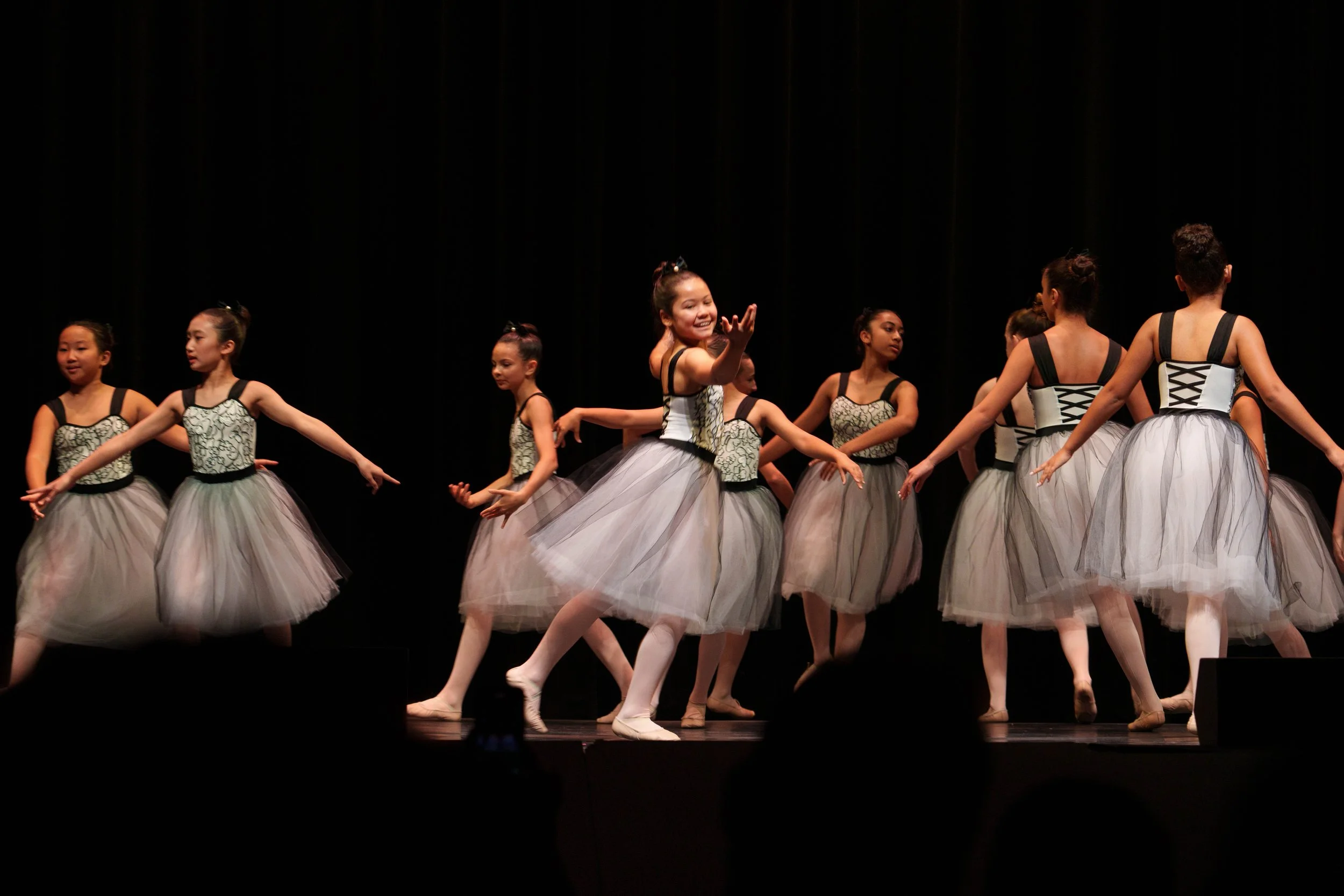 Young girls in ballet costumes performing on stage during a dance recital.