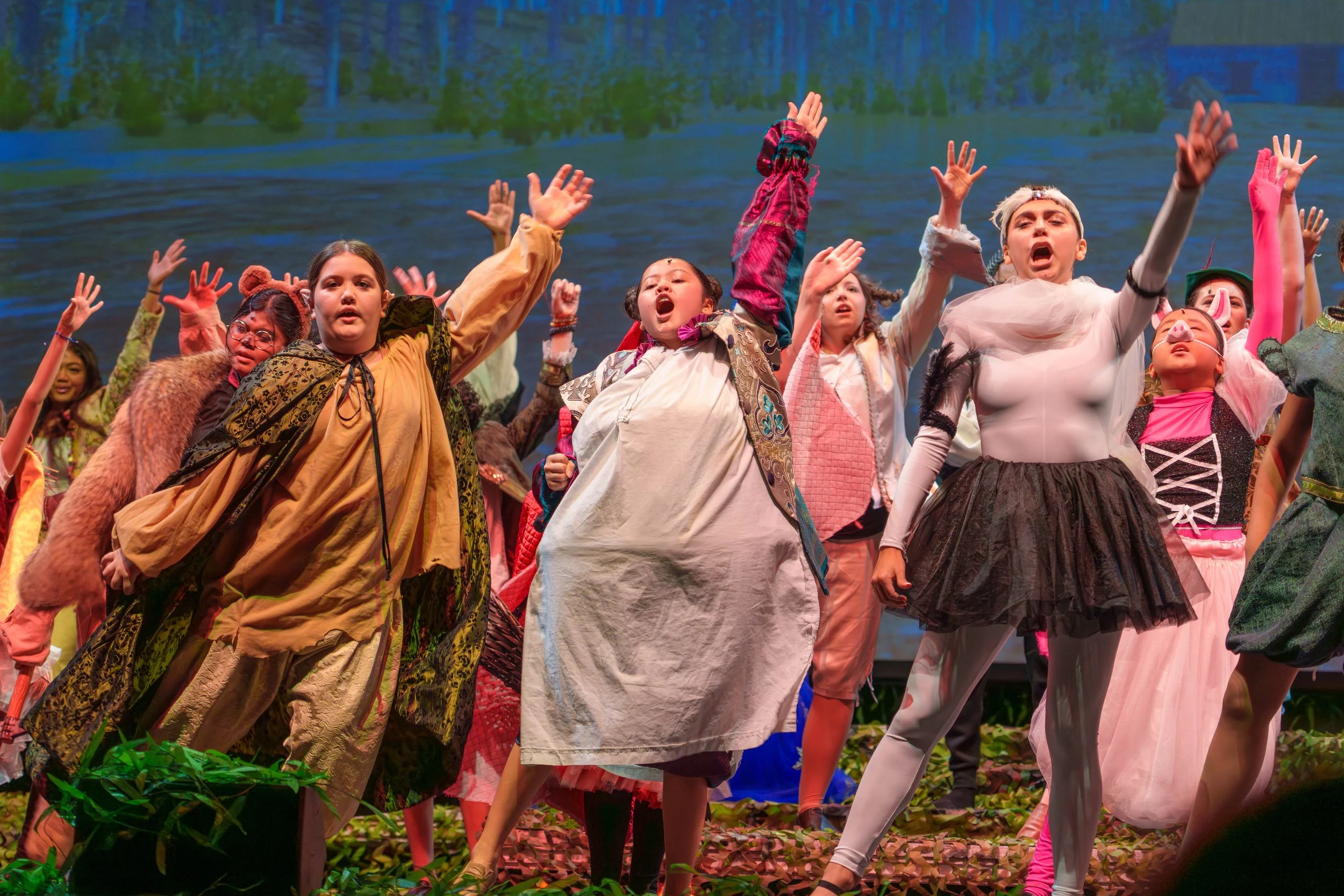 Children dressed in colorful costumes performing on stage during a theatrical play.