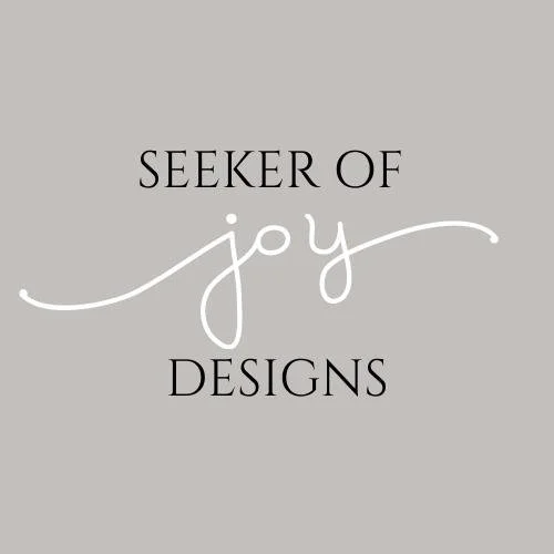 Gray background with black and white text reading "Seeker of joy Designs" in a combination of serif and cursive fonts.