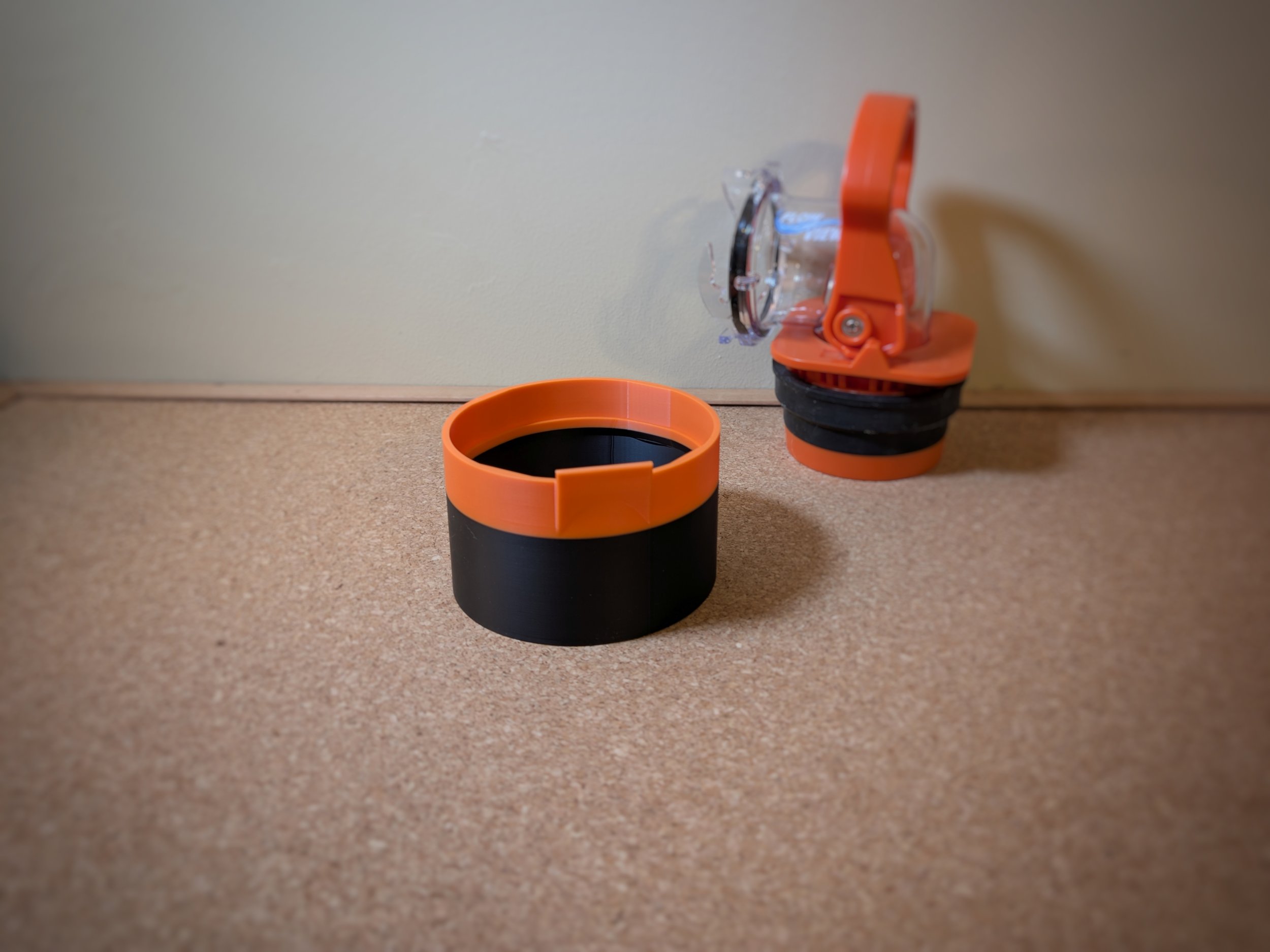 In the foreground is a deep orange and black sewer cap designed to fit the Camco Rhino RV Sewer Adapter Pro product, which is also seen in background of the picture