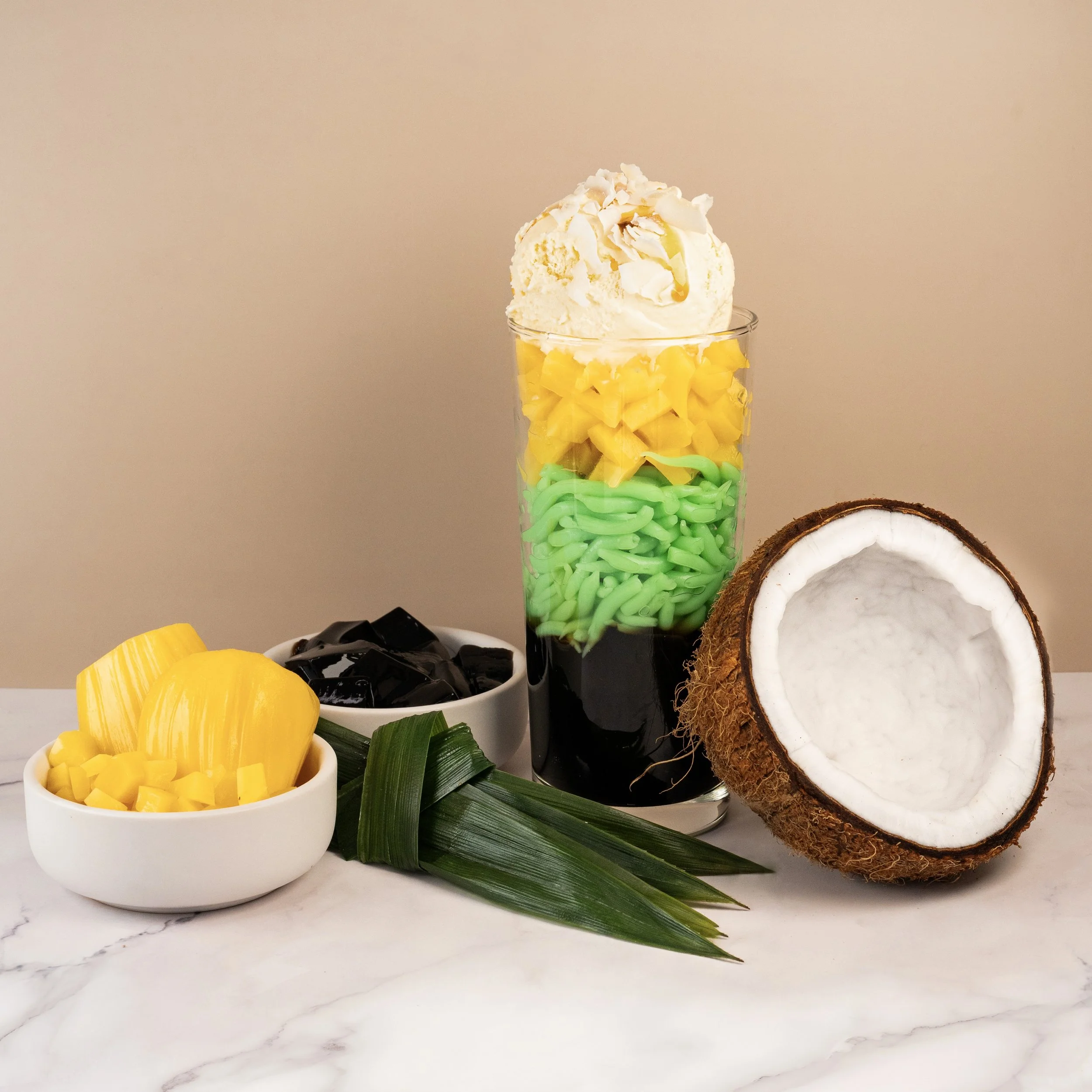 Iced Cendol with pandan noodles, grass jelly and mango topped with coconut flakes