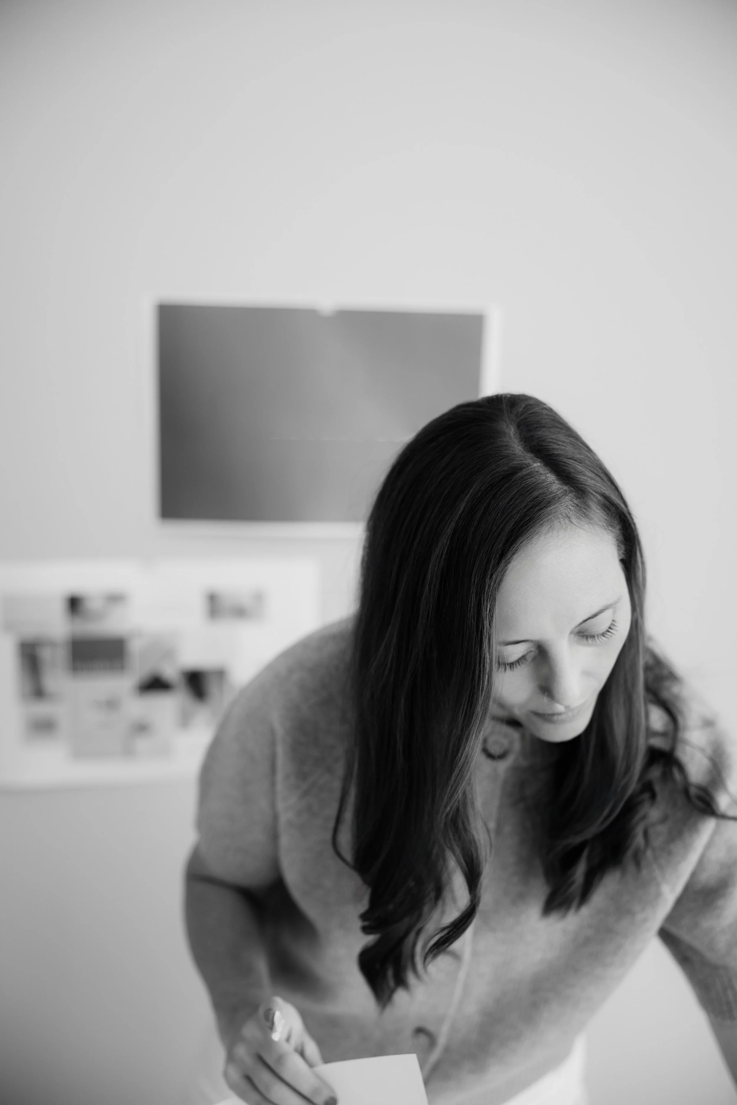 Woman leaning over desk moving papers and organizing brand board