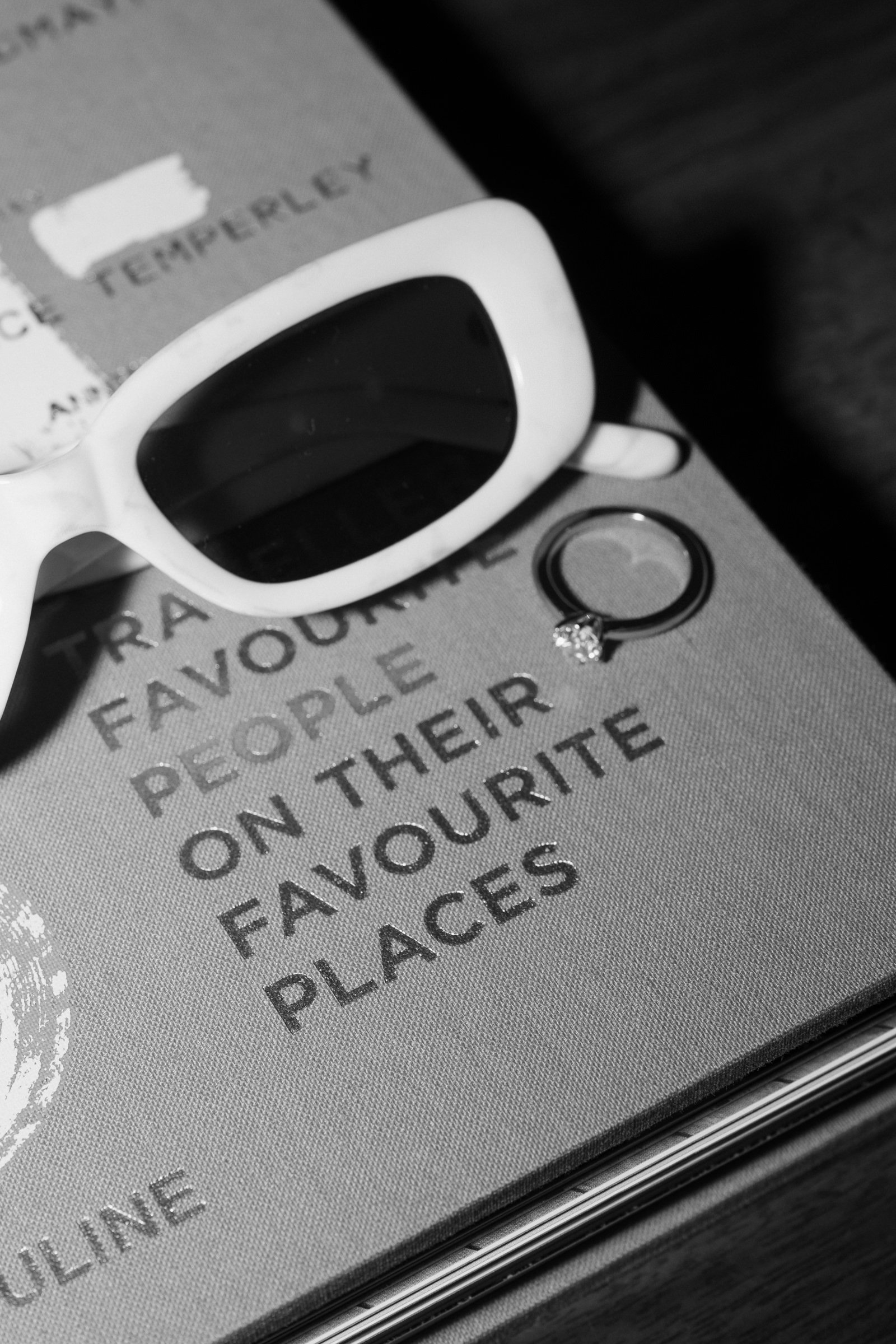 Close-up of a textured surface with a pair of white sunglasses, a circular ring, and partially visible text including words such as 'favorite', 'people', 'on their', and 'faces'.