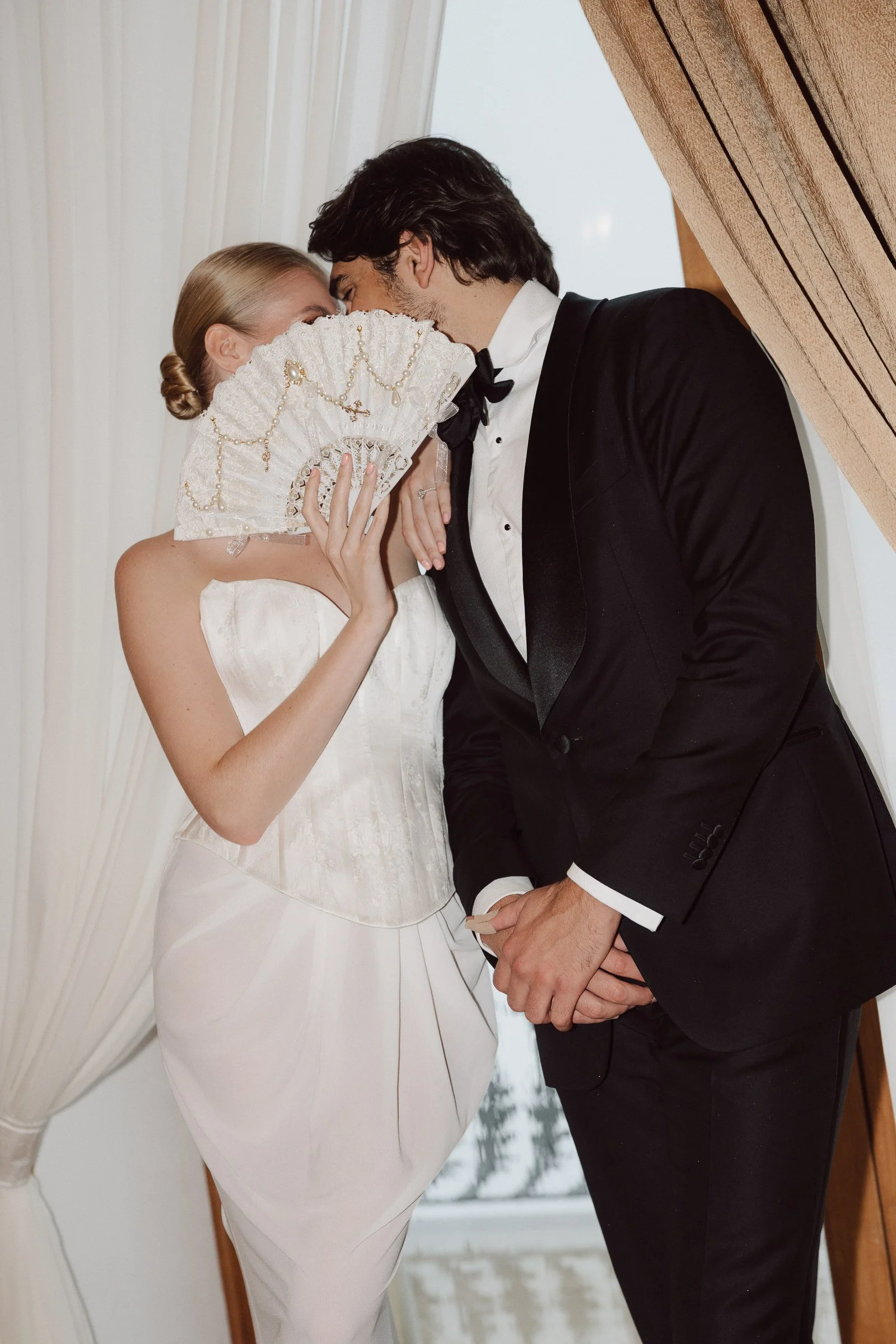 A bride and groom hold hands and gently touch foreheads while sharing their wedding moment.