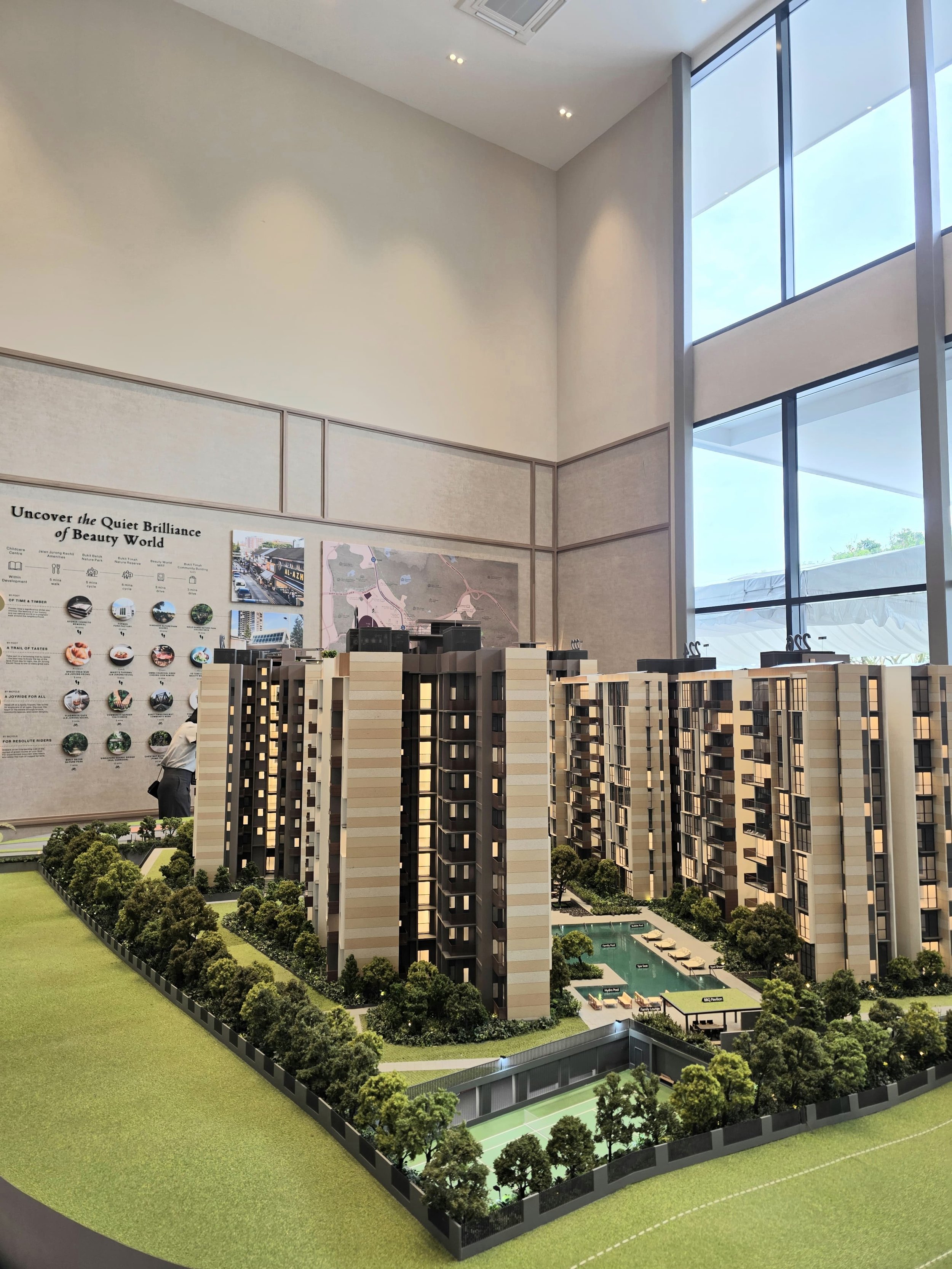 Architectural scale model of a Singapore new launch condo, showing high-rise buildings, landscaped greenery, swimming pool, and tennis courts at a showflat.