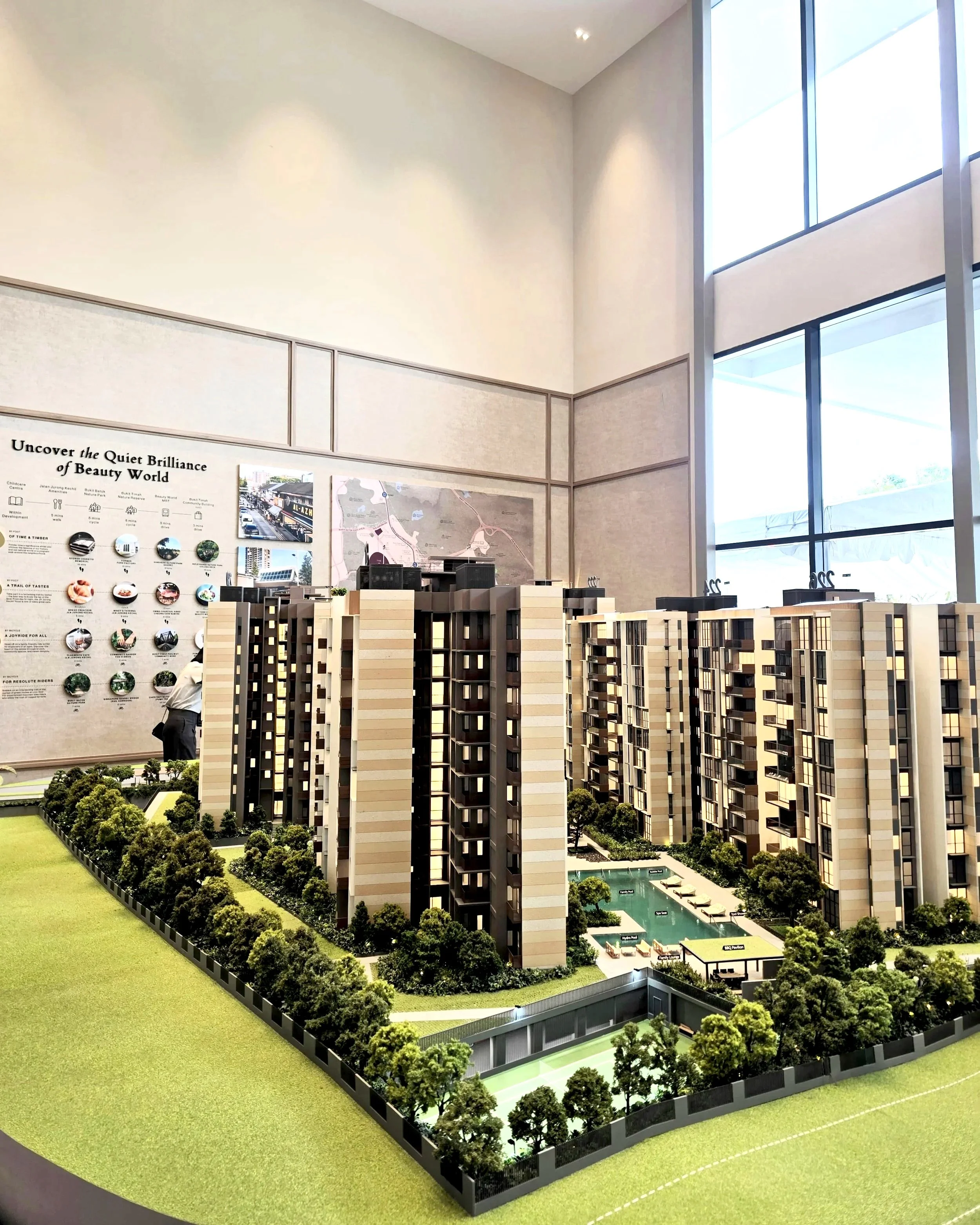 Architectural scale model of a Singapore new launch condo, showing high-rise buildings, landscaped greenery, swimming pool, and tennis courts at a showflat.