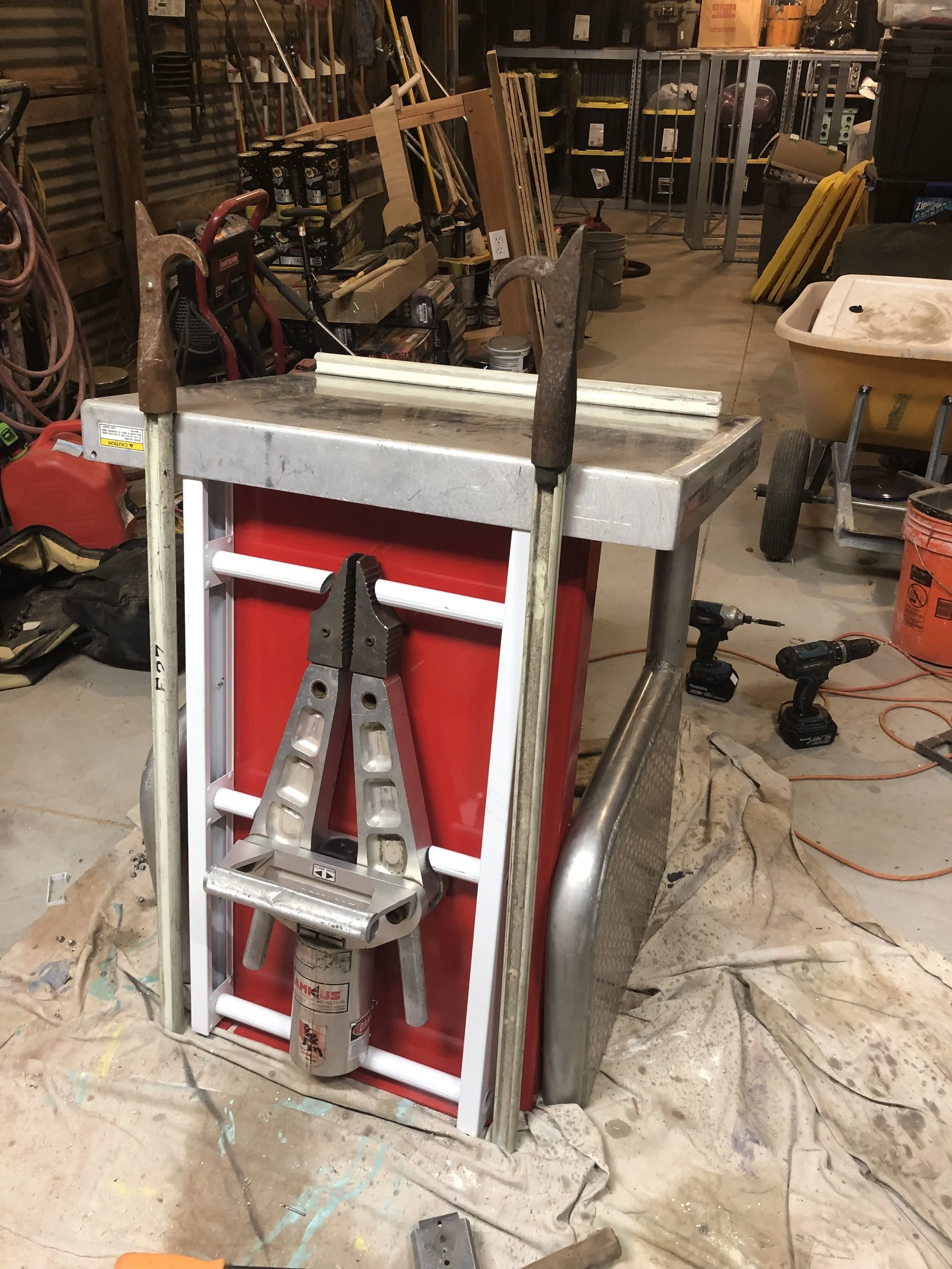 A workshop with a workbench, two chisels, a level, and a toolbox, with various tools and equipment in the background.