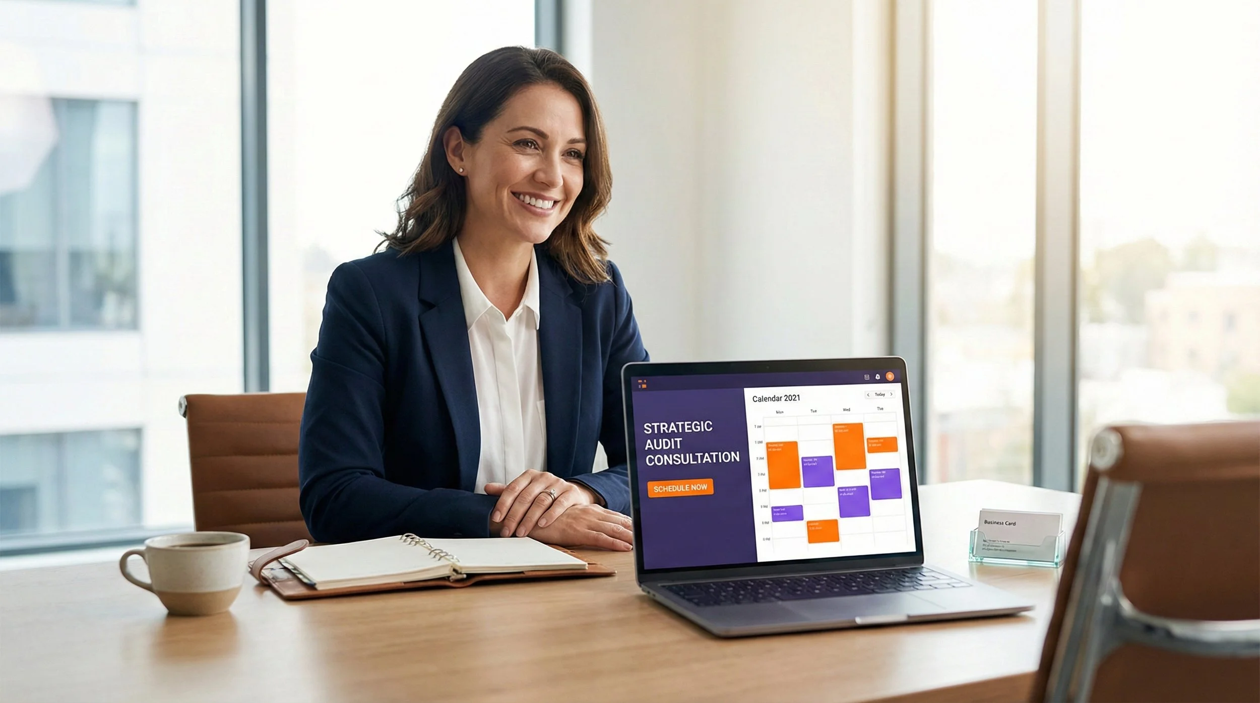 Une femme d'affaires souriante assise à une table devant un ordinateur portable affichant un calendrier pour 2021, dans un bureau lumineux avec de grandes fenêtres.