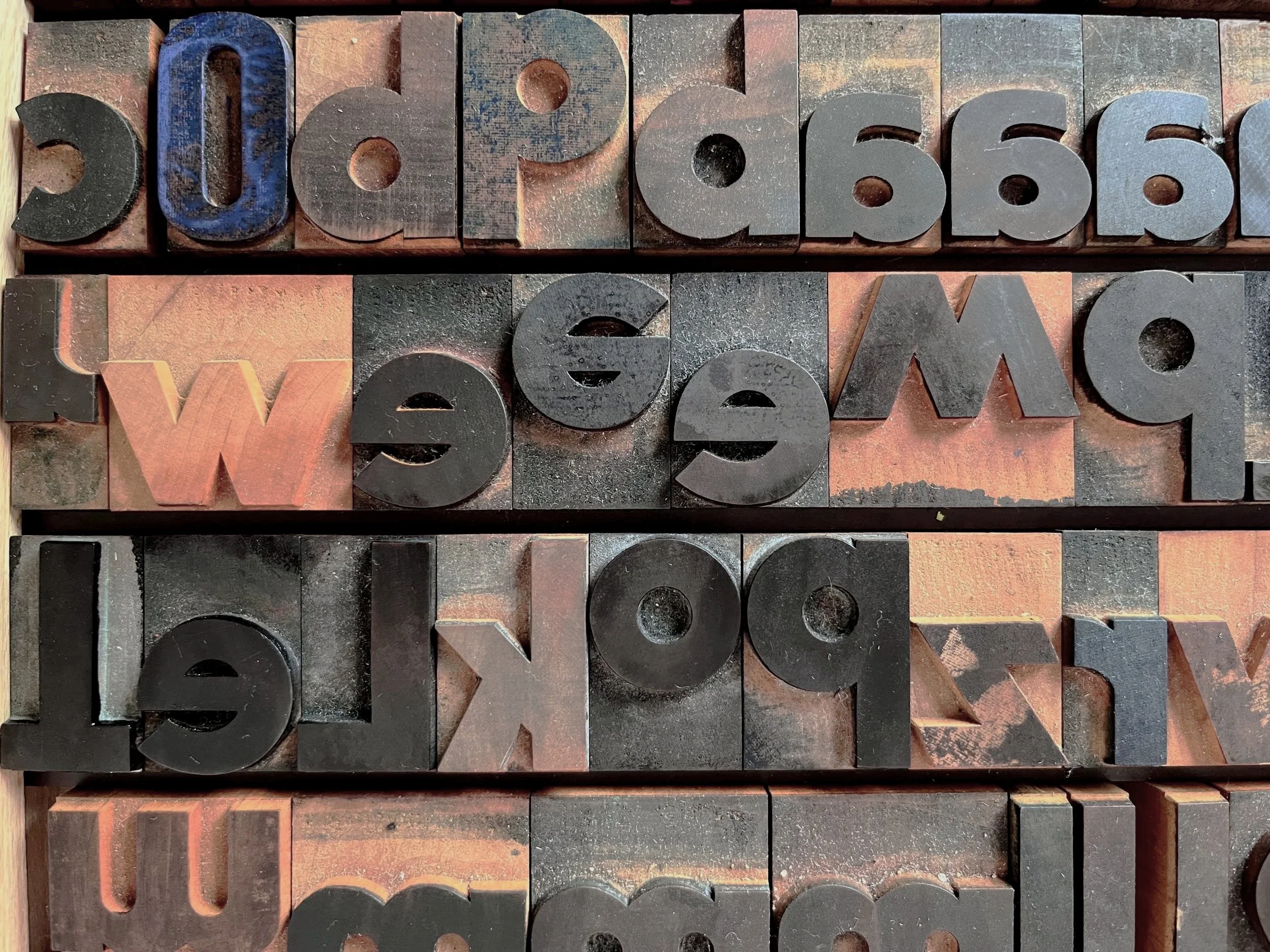 Detailansicht eines Workshops im wach Kunstraum mit Vintage-Letterpress-Blöcken aus Buchstaben und Zahlen in Reihen; detailed view of a workshop at wach Kunstraum with vintage letterpress blocks of letters and numbers stacked in rows.