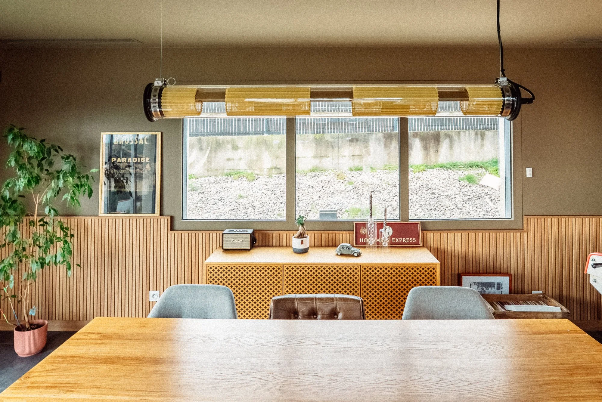 Salle à manger avec un soubassement en tasseaux de bois, un mélange de fauteuil Maison du monde et de fauteuils chiné. Suspensions DCW In the tube. Peinture Ressource R196 Le marais