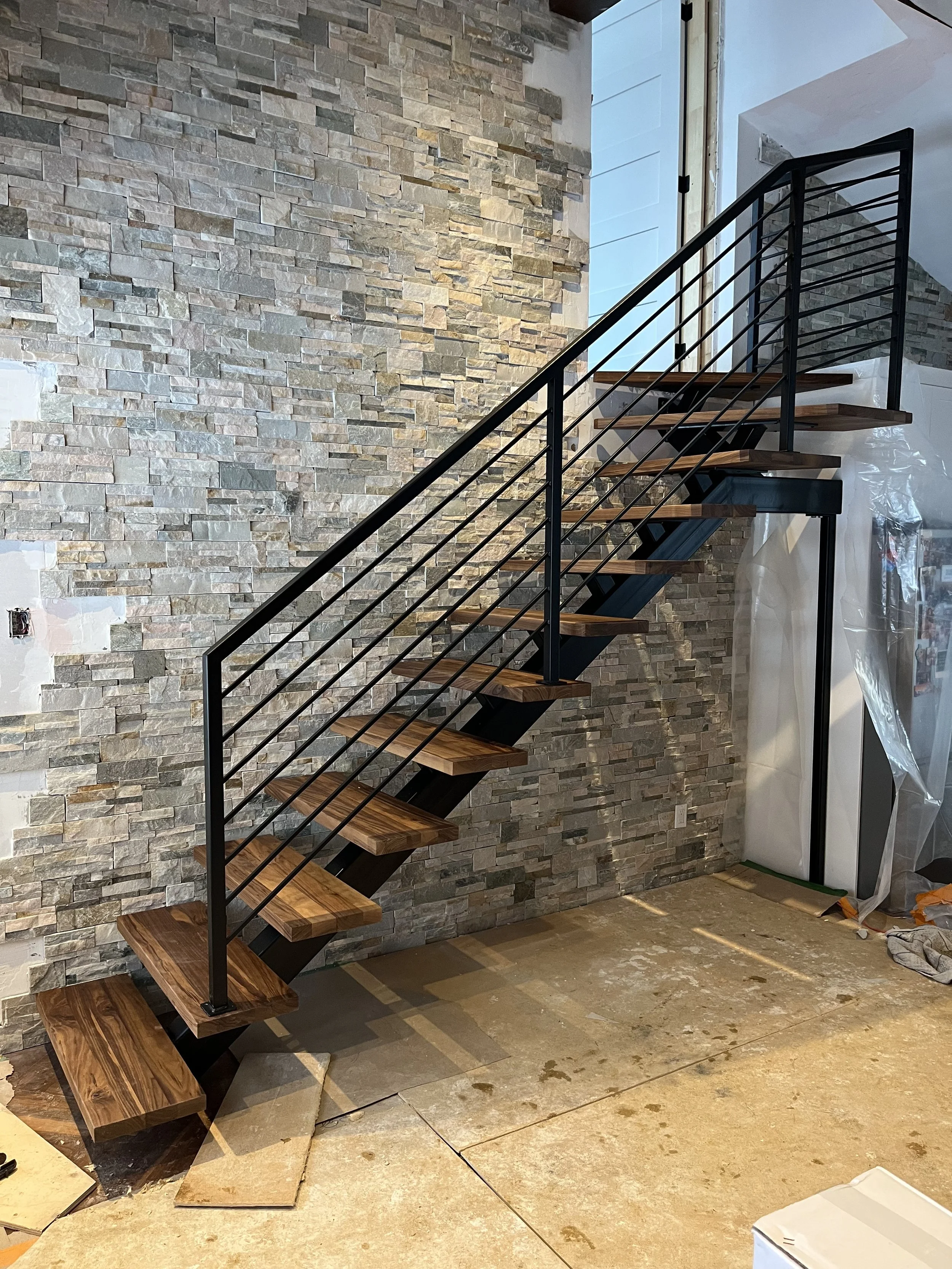 central stringer with walnut treads and horizontal black steel railings.