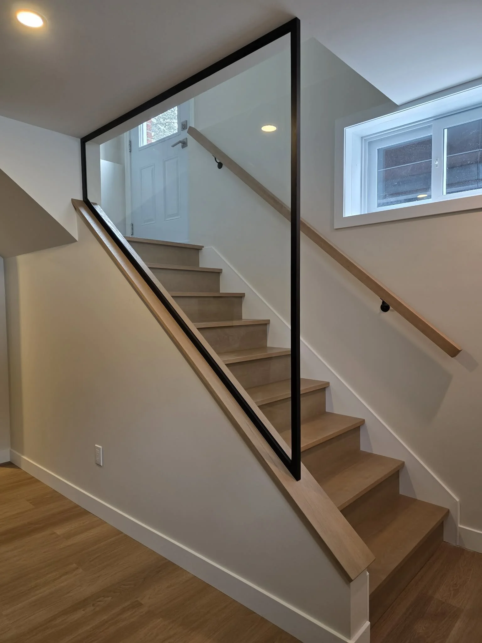 Custom red oak staircase with a wooden handrail and a glass panel baluster