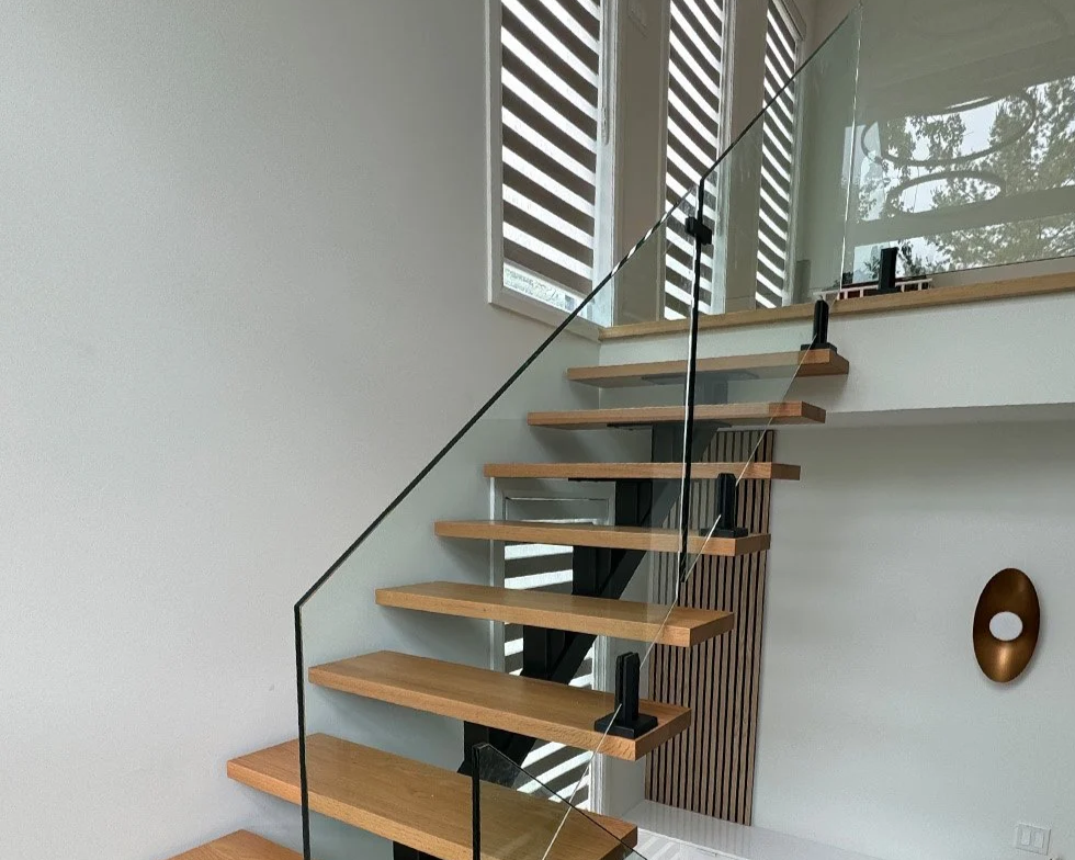 Black central stringer with red oak treads and glass railings on spigots