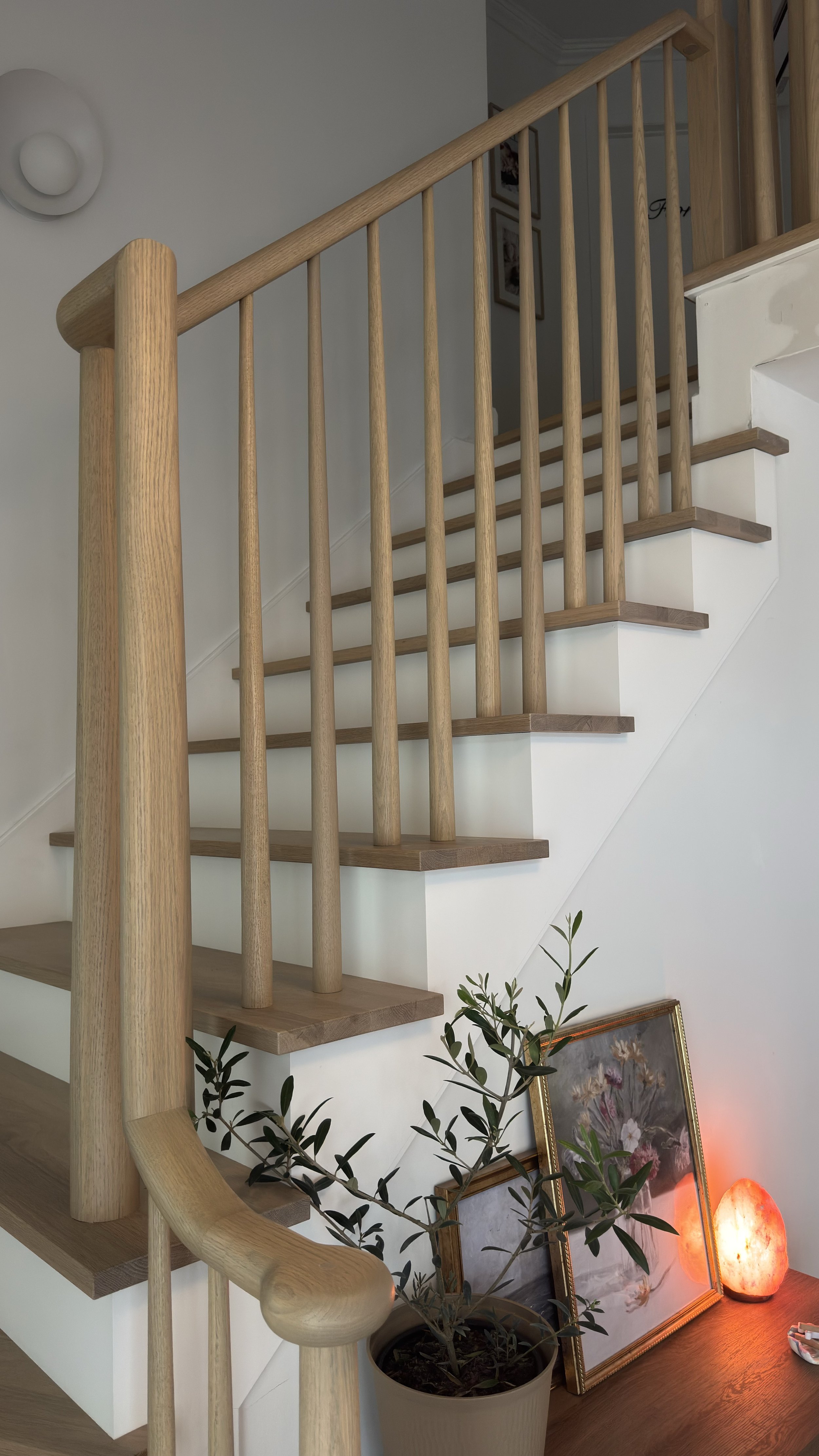 Wooden staircase with tapered wood spindles, a curved handrail and a white oak staircase color matched to a white oak floor.