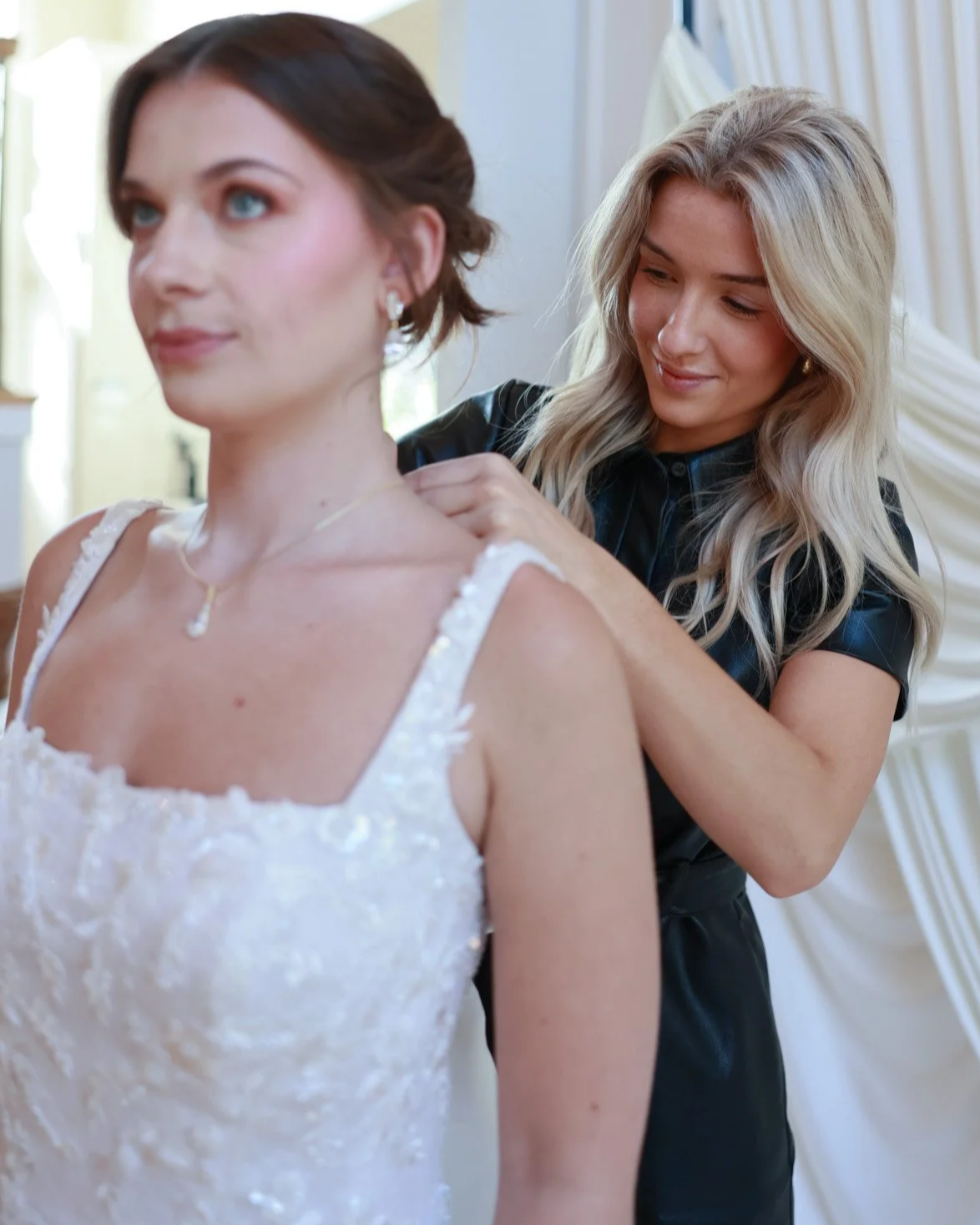 Bride trying on lace wedding gown during bridal dress appointment