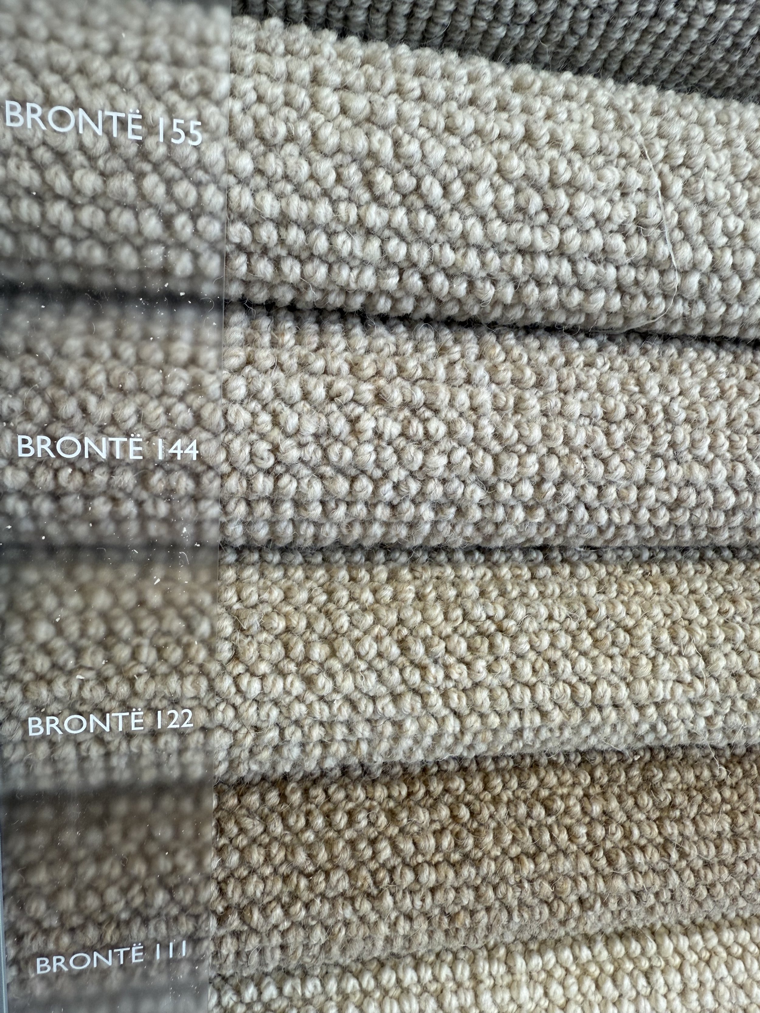 Cormar Carpet - Close-up of beige carpet samples labeled Brontë 155, 144, 122, and 111, showing textured, loop pile surface.