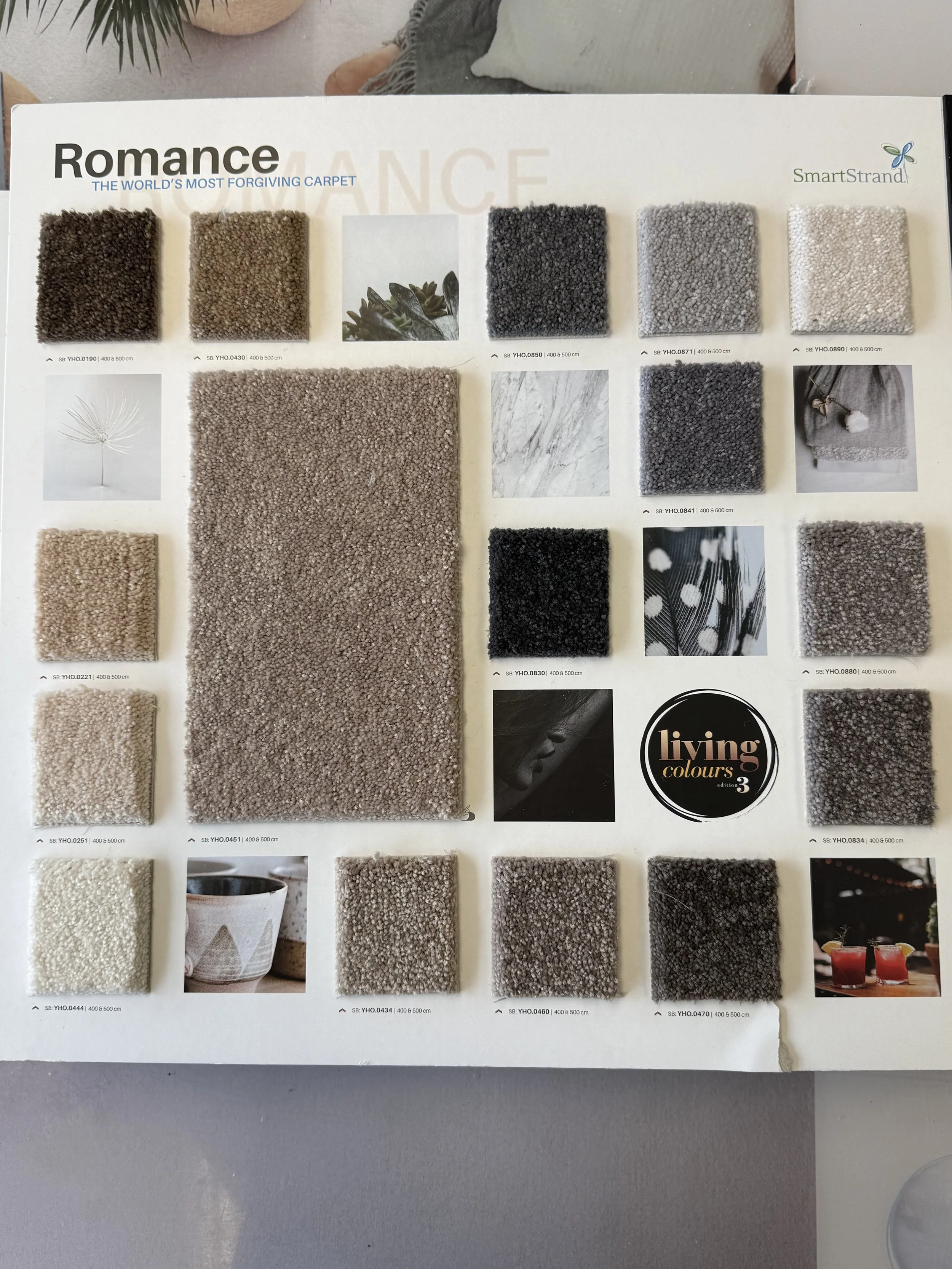 SmartStrand Carpet - A carpet sample catalog titled 'Romance' featuring various swatches of textured carpet in neutral colors, along with images of decor items 