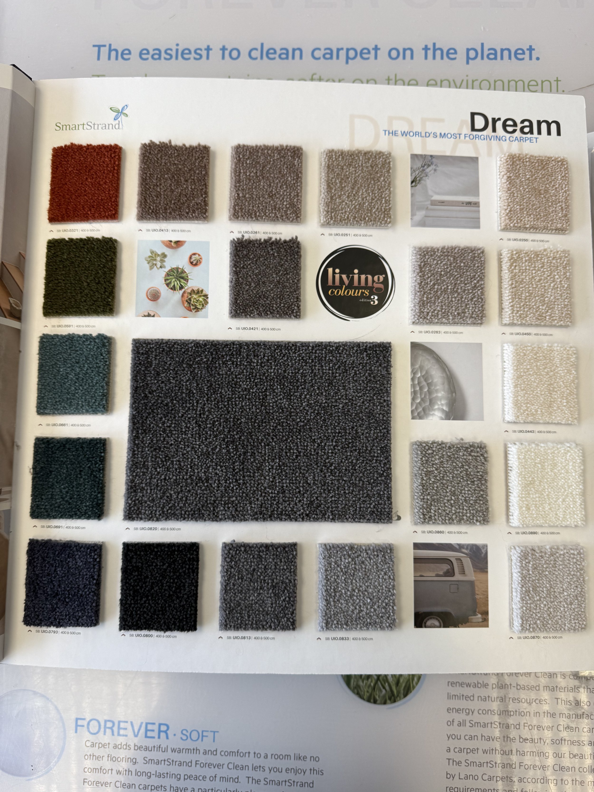 SmartStrand Carpet - A carpet sample catalog displaying various colors and textures of carpet tiles, with some images of outdoor plants, a caravan, and a black circle logo for Living Colors.