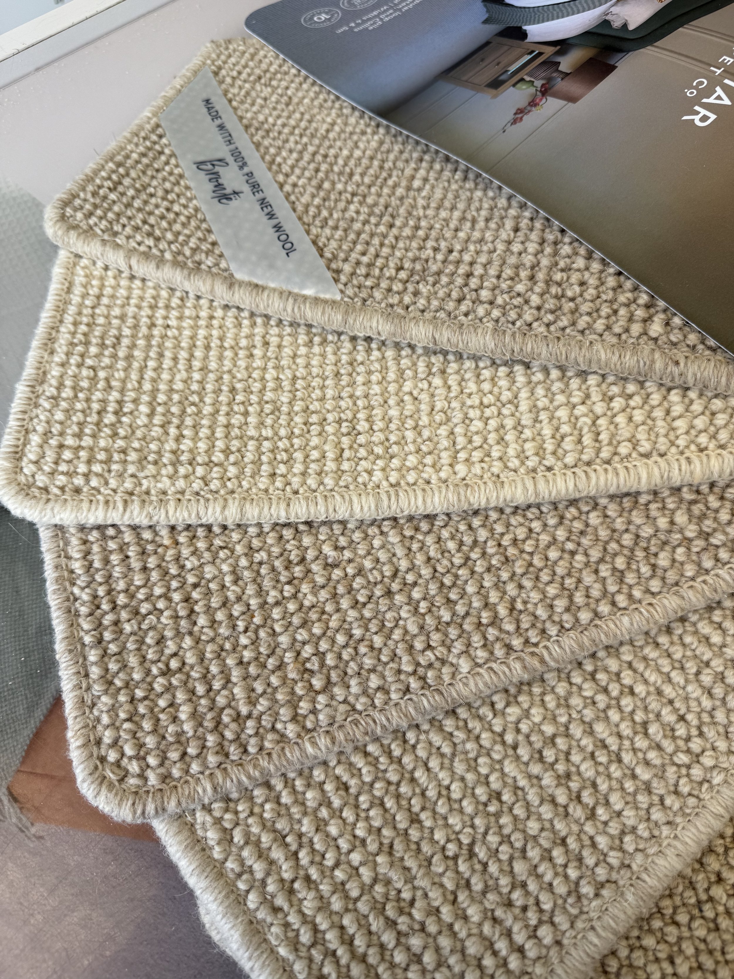 Cormar Carpet - Three beige textured rug samples stacked on top of each other on a glass table.