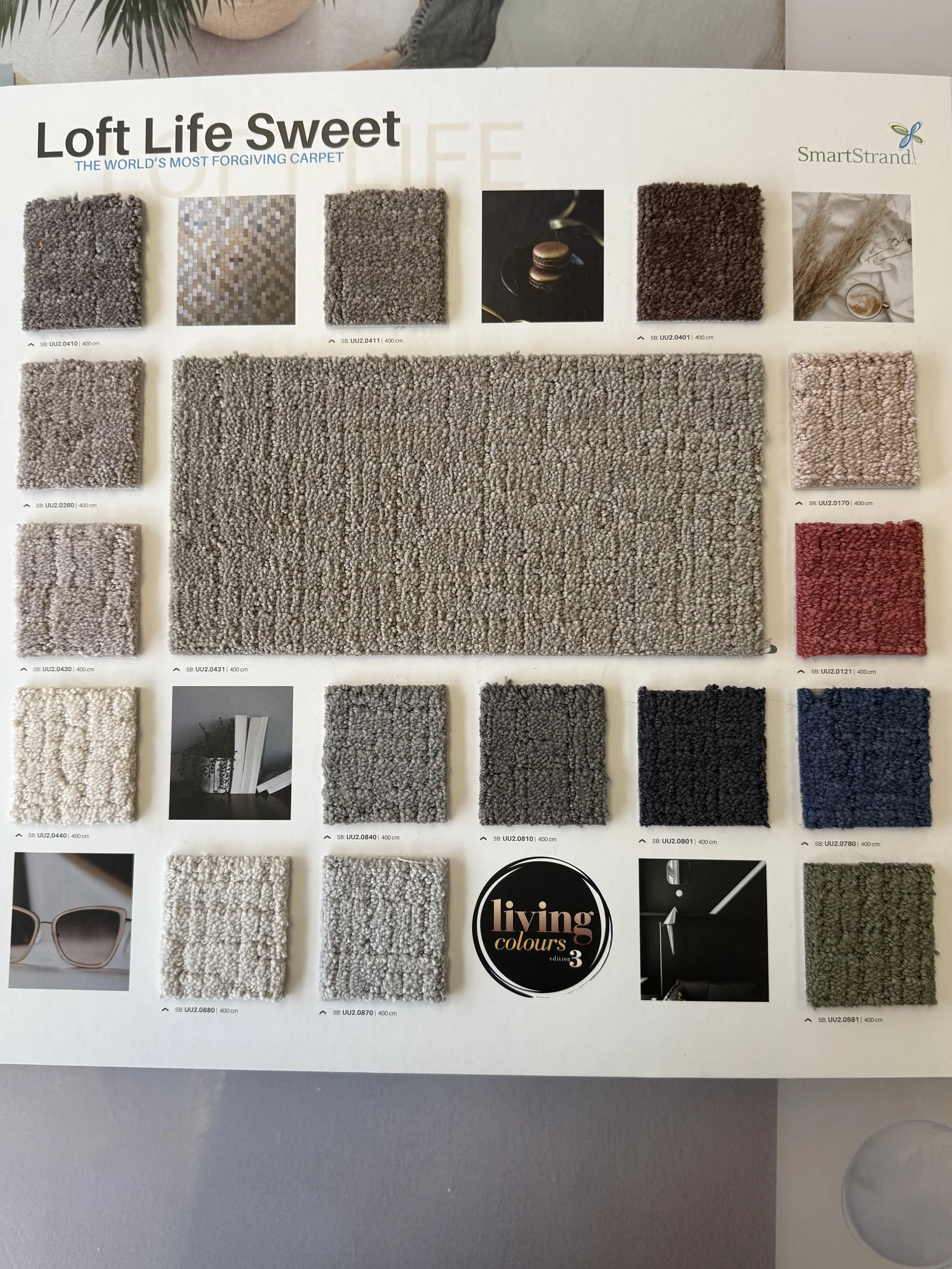 SmartStrand Carpet - Swatch sample sheet of carpet tiles from the Loft Life Sweet collection by SmartStrand, featuring various shades of gray, beige, white, red, black, blue, and green, with some close-up textures and label details.