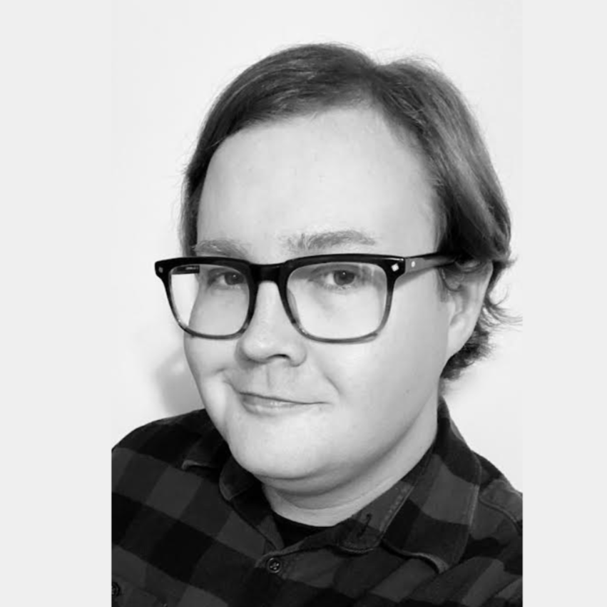 Liam Gosson - Black and white portrait of a person with glasses and short hair, wearing a checkered shirt, smiling slightly.